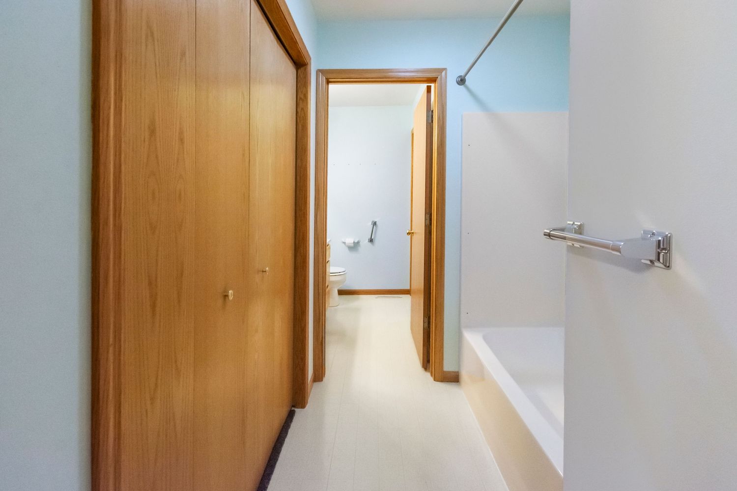 Interior hallway with honey-colored wood trim and doors against light blue walls.