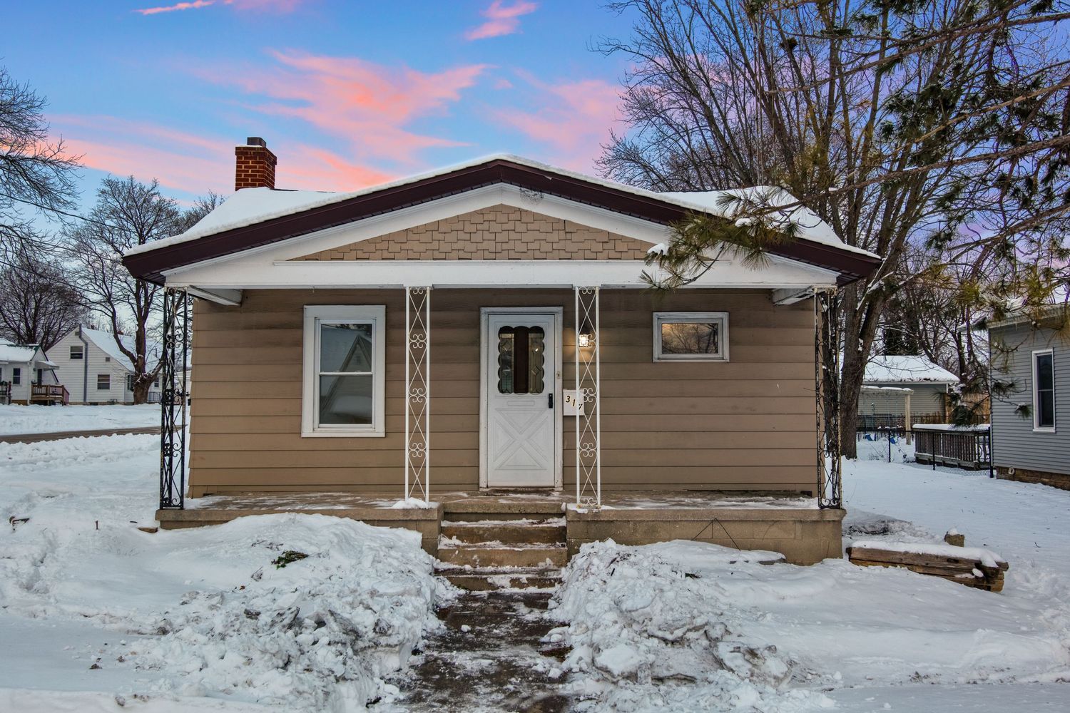 Tan residential home with white trim viewed from side angle in snowy winter conditions.