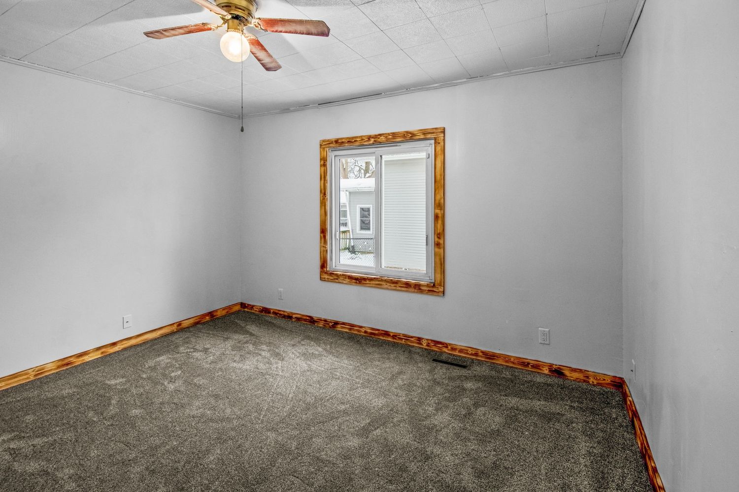 Empty room interior showing gray carpet, white walls, wood trim, and ceiling fan in different angles.