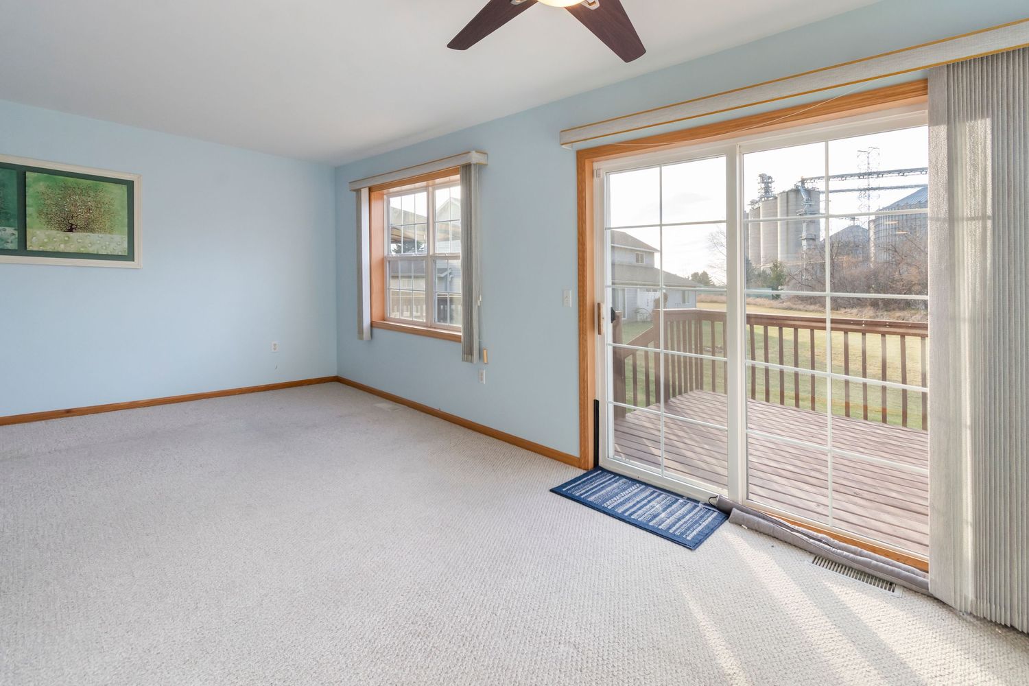 Interior view of a spacious bedroom with hardwood floors, white walls, and large windows overlooking a scenic view.