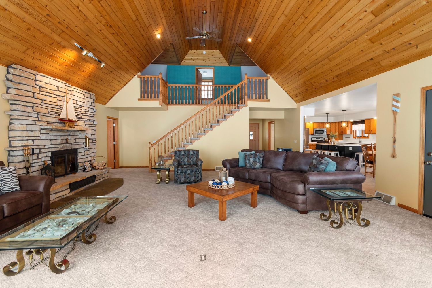 Panoramic view of a rustic living room with wood-paneled ceiling, stone fireplace, and comfortable seating areas.