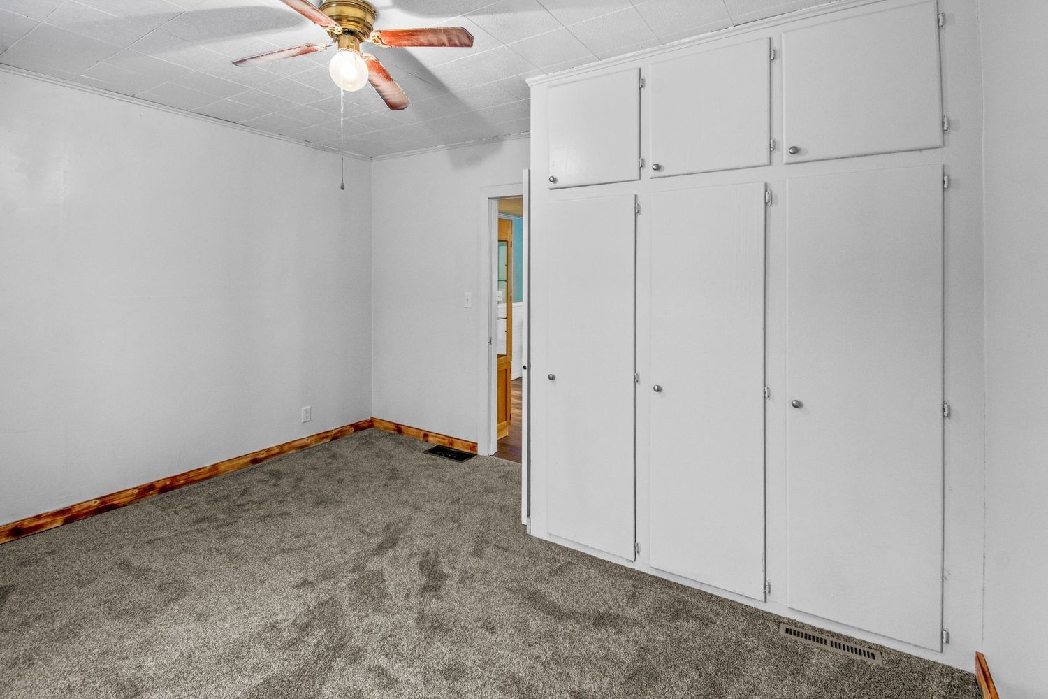 Carpeted bedroom with white built-in closets and a ceiling fan.