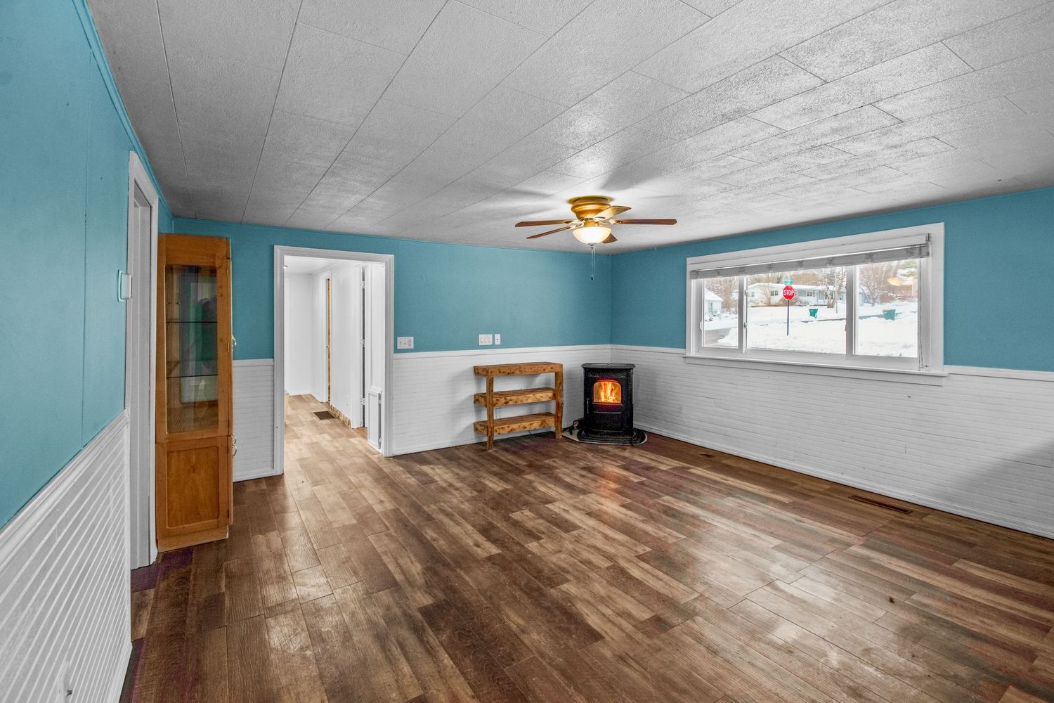 Spacious room with teal walls, hardwood floors and large windows providing natural light.