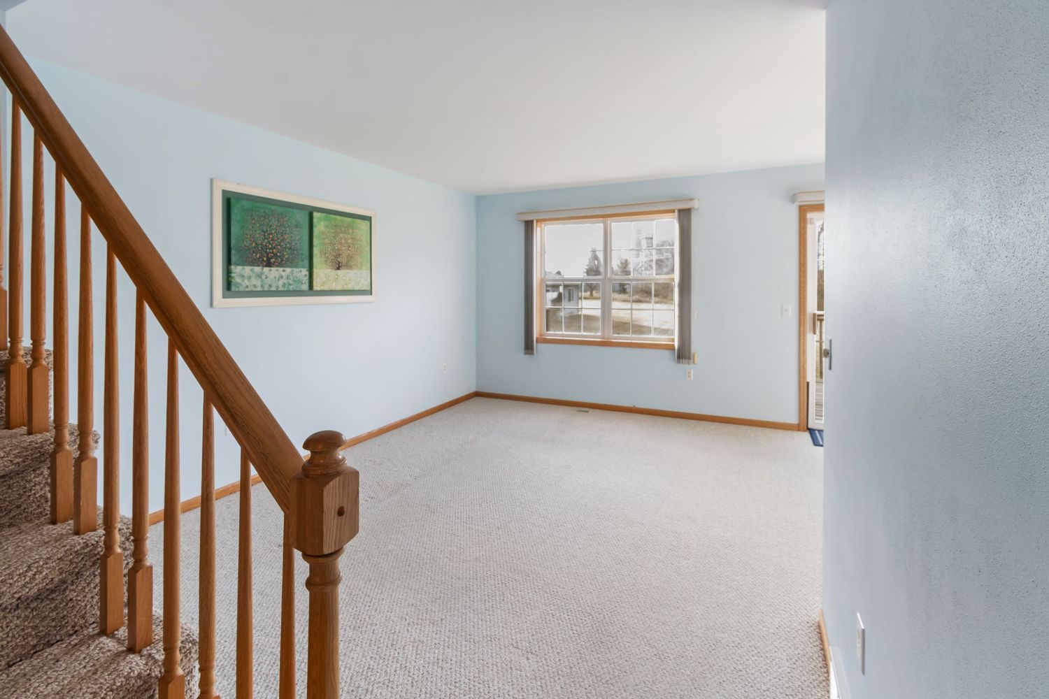 Open concept living area with wooden staircase railing and light blue painted walls.