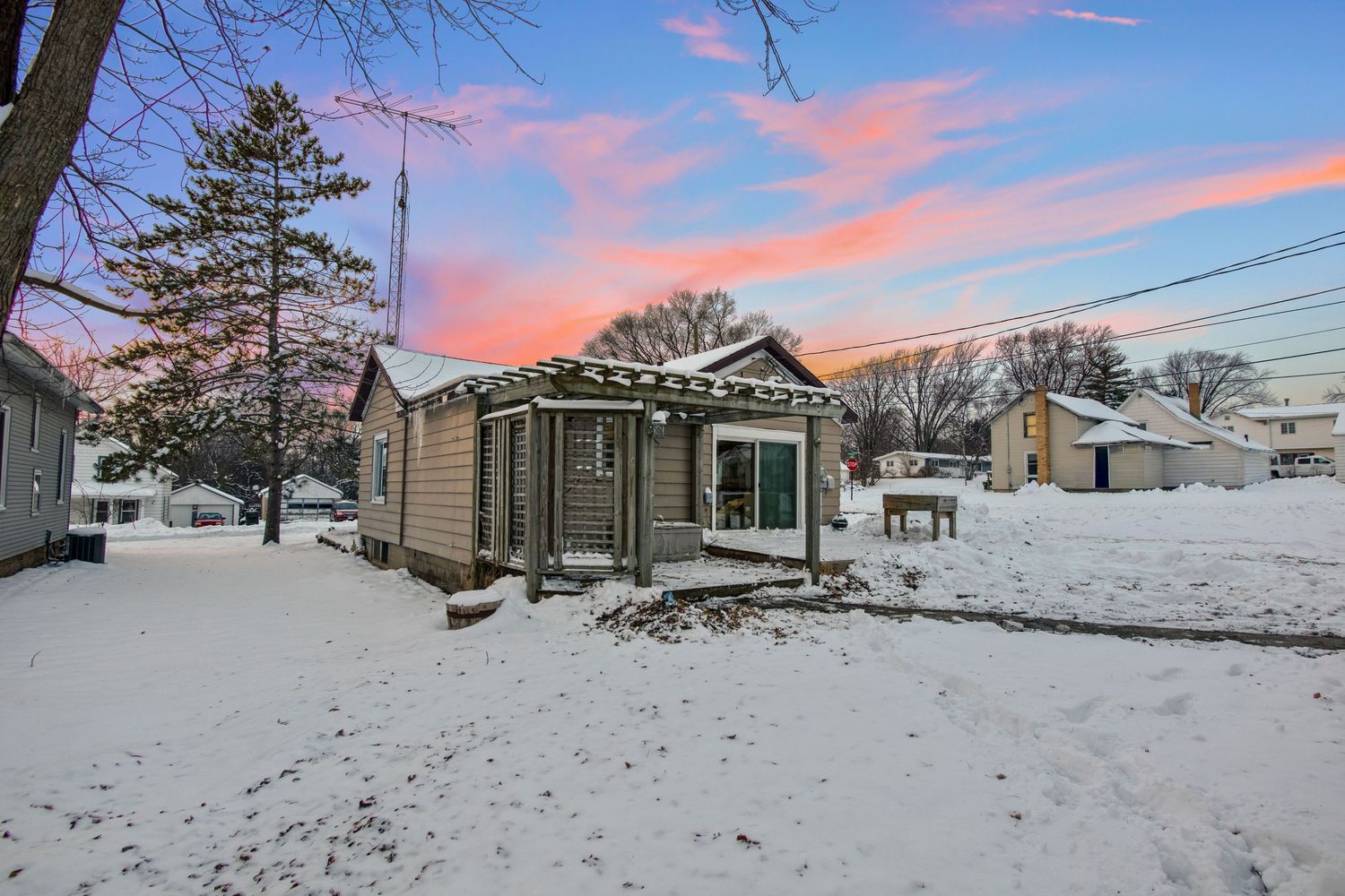 Winter panorama of residential homes with snow covered yards during a colorful sunset.
