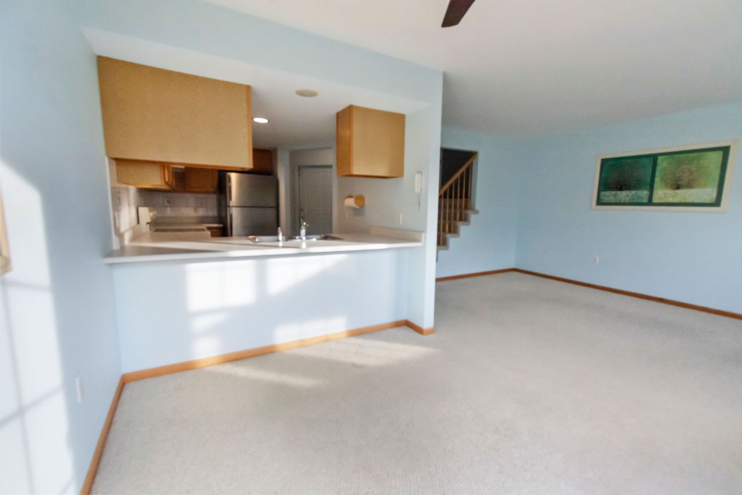 Long empty hallway with white walls, wooden trim, and carpet flooring leading to multiple doorways.