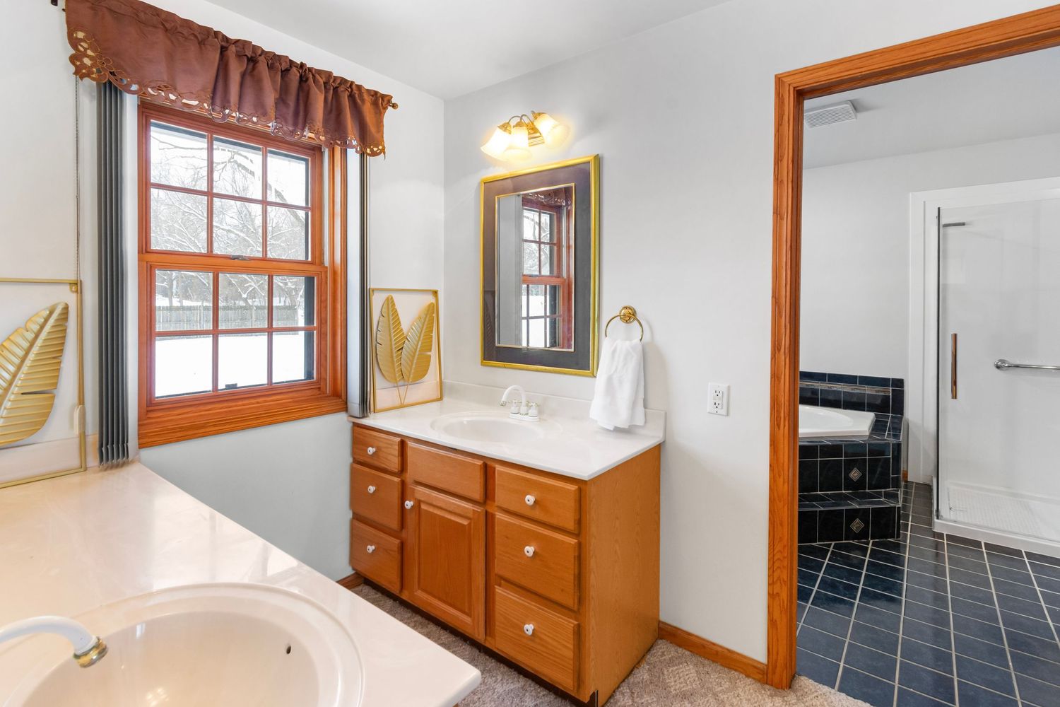Bathroom interior with wooden vanity, mirror, and window featuring natural light.