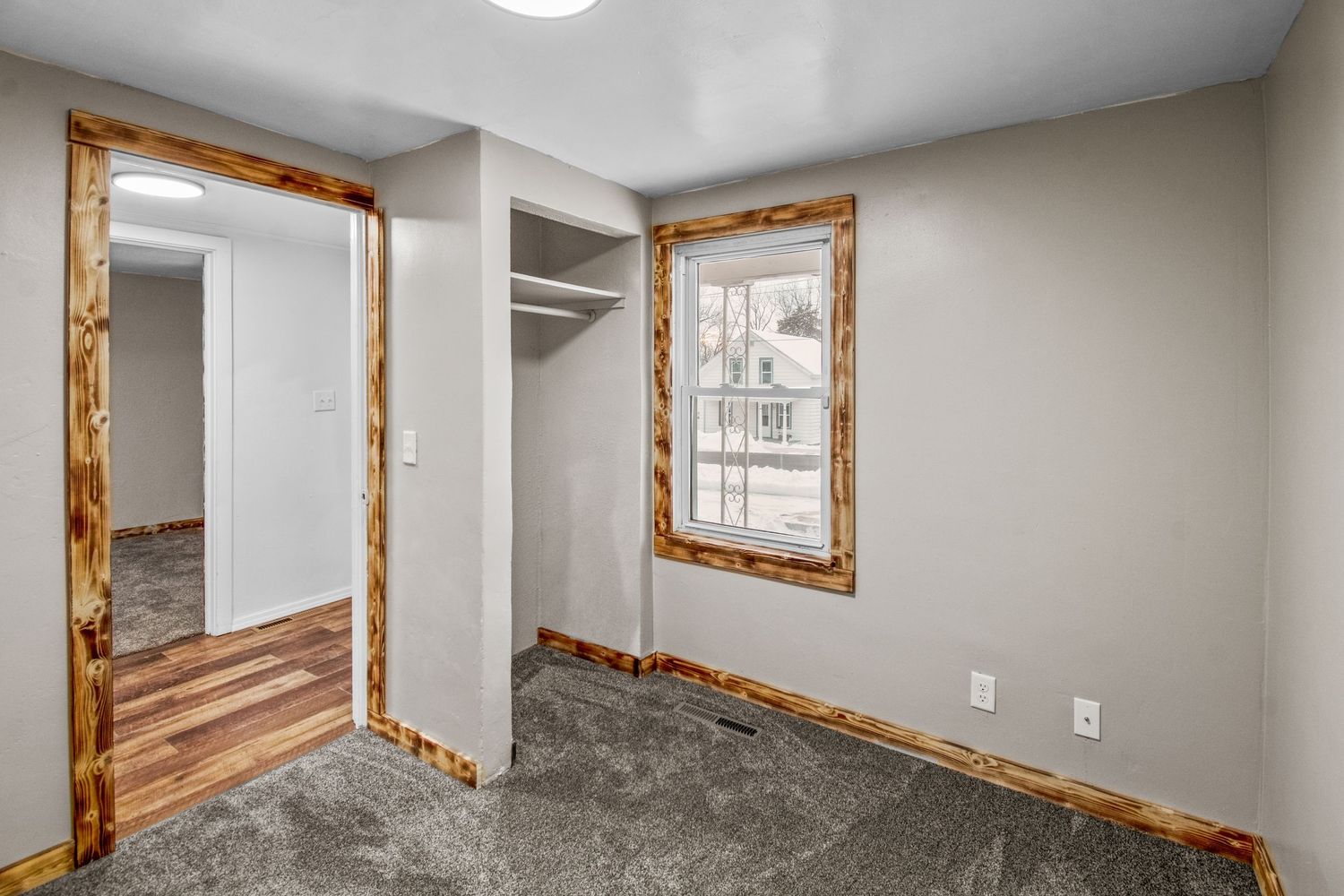 Modern basement hallway with rustic wood-trimmed mirrors and white walls creates an inviting transitional space.