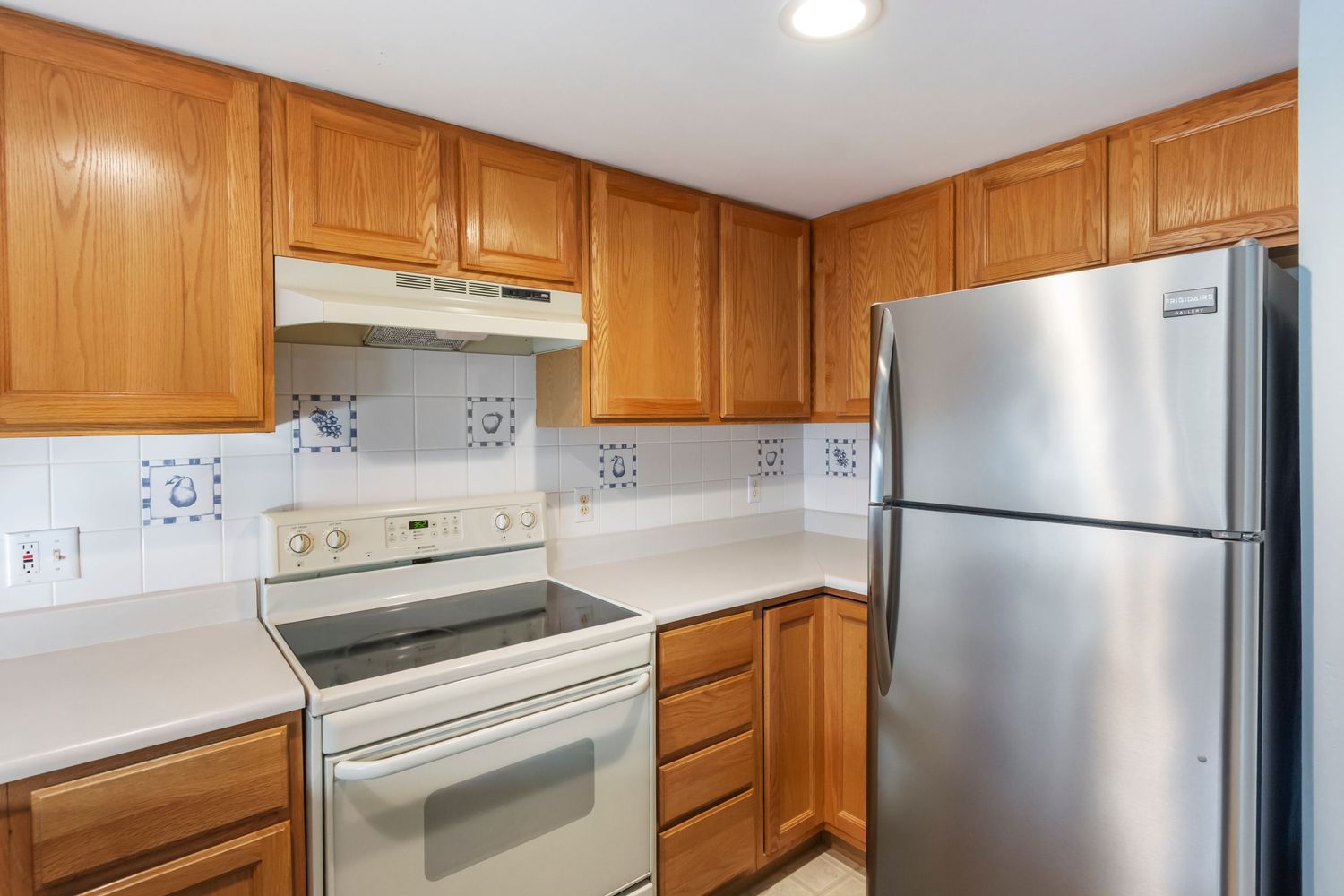 Spacious kitchen with honey oak cabinets, white appliances, and recessed lighting.