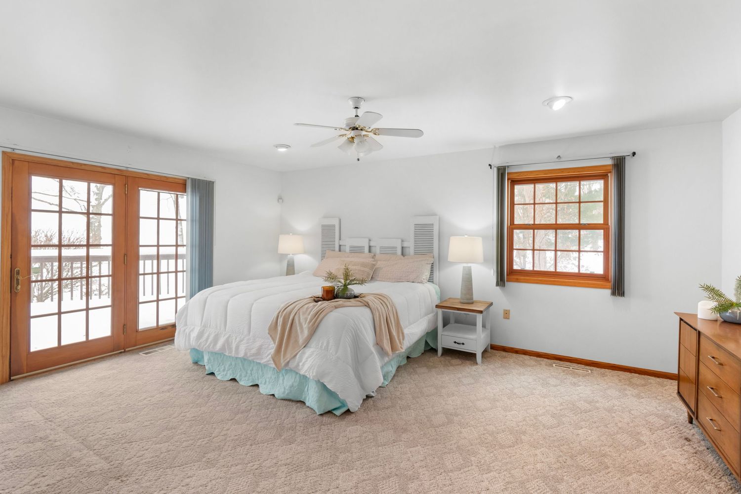 Large master bedroom with vaulted ceiling, wood-framed windows, and plush carpeting in neutral tones.