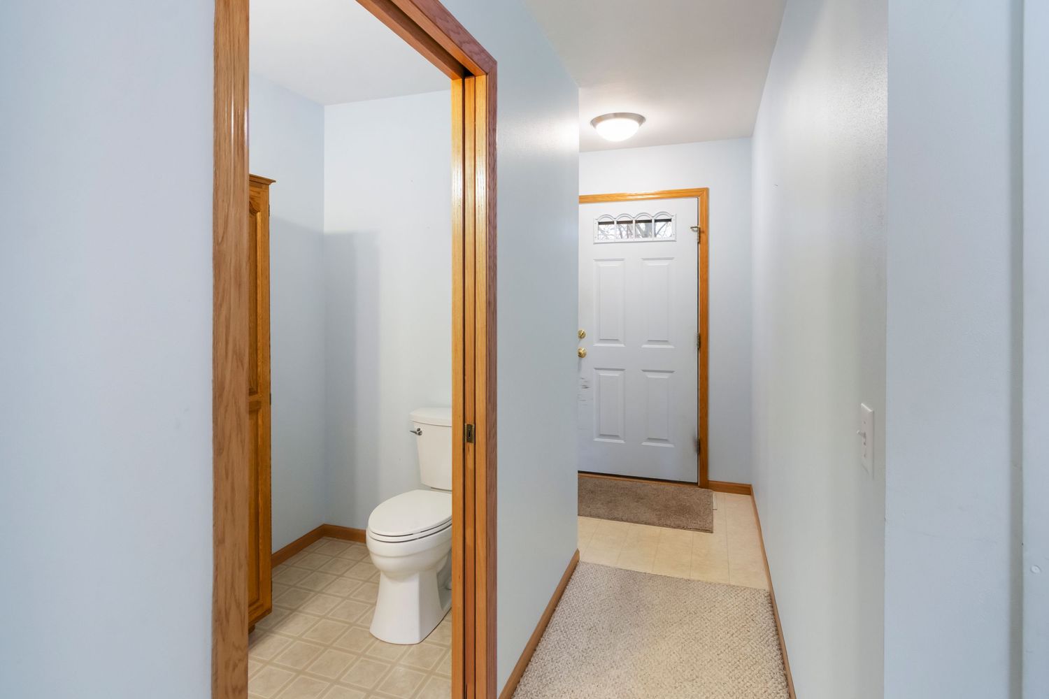 Long hallway with white walls, wooden trim, and ceiling-mounted light fixtures.