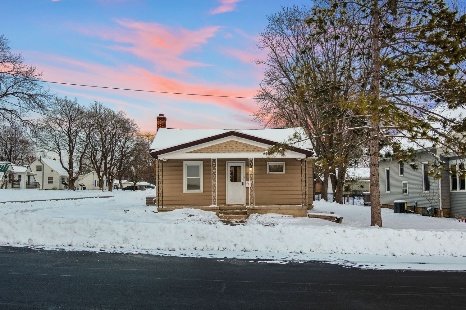Beige house with attached garage photographed during winter sunset with pink sky.