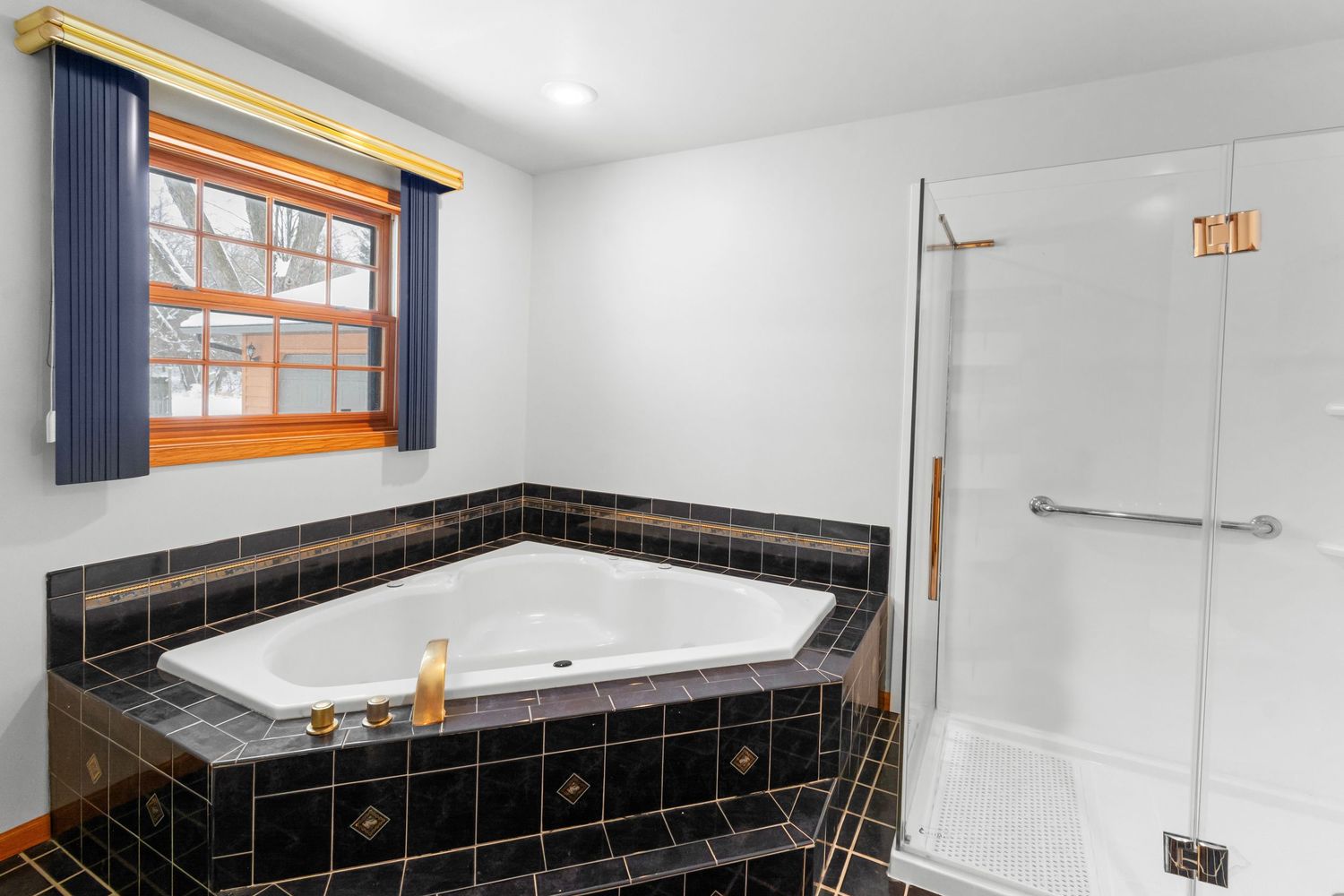 Luxurious bathroom with black tile accents, large soaking tub, and modern fixtures.