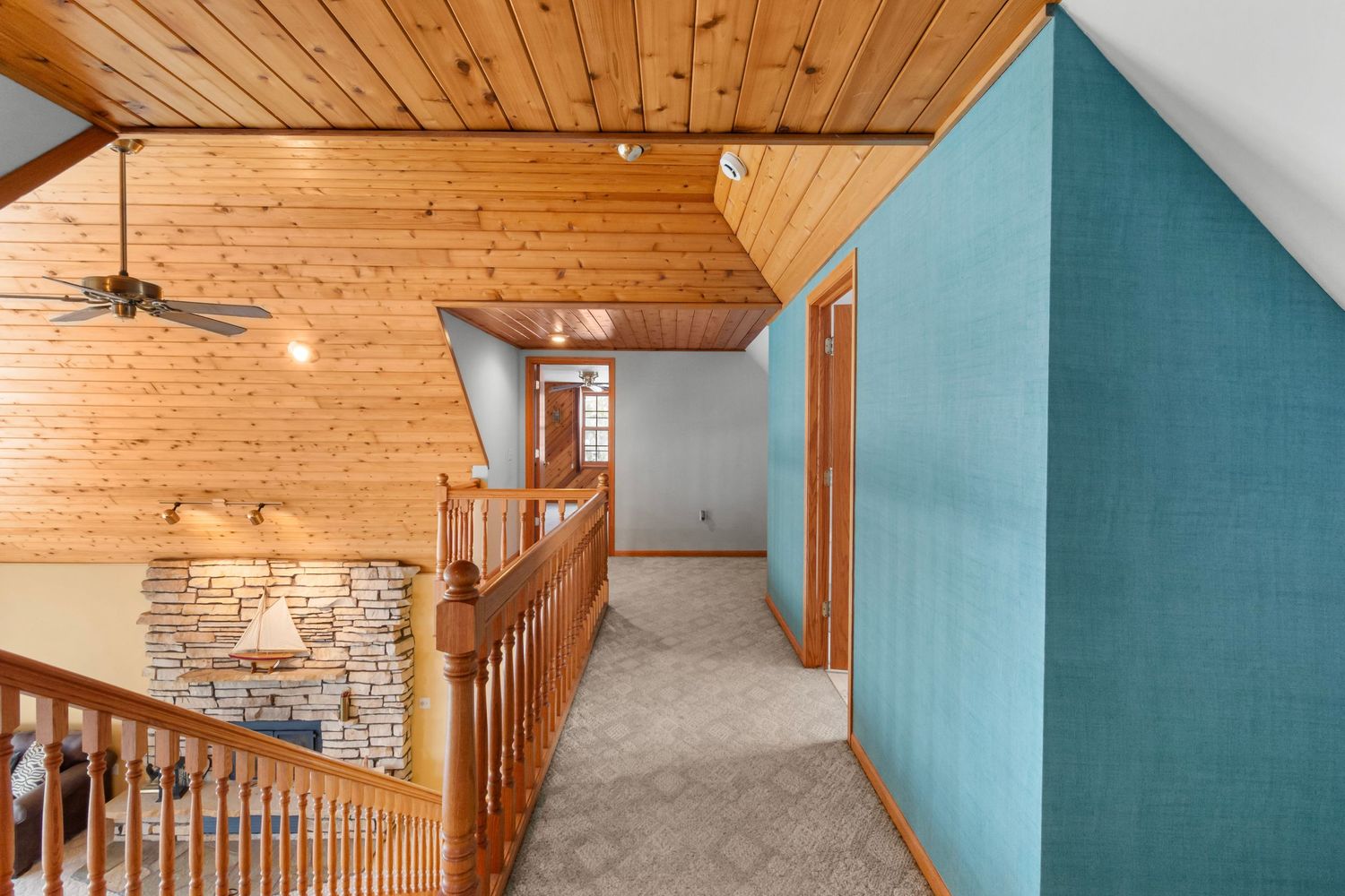Living space with teal accent wall, wooden ceiling, and stone fireplace feature.