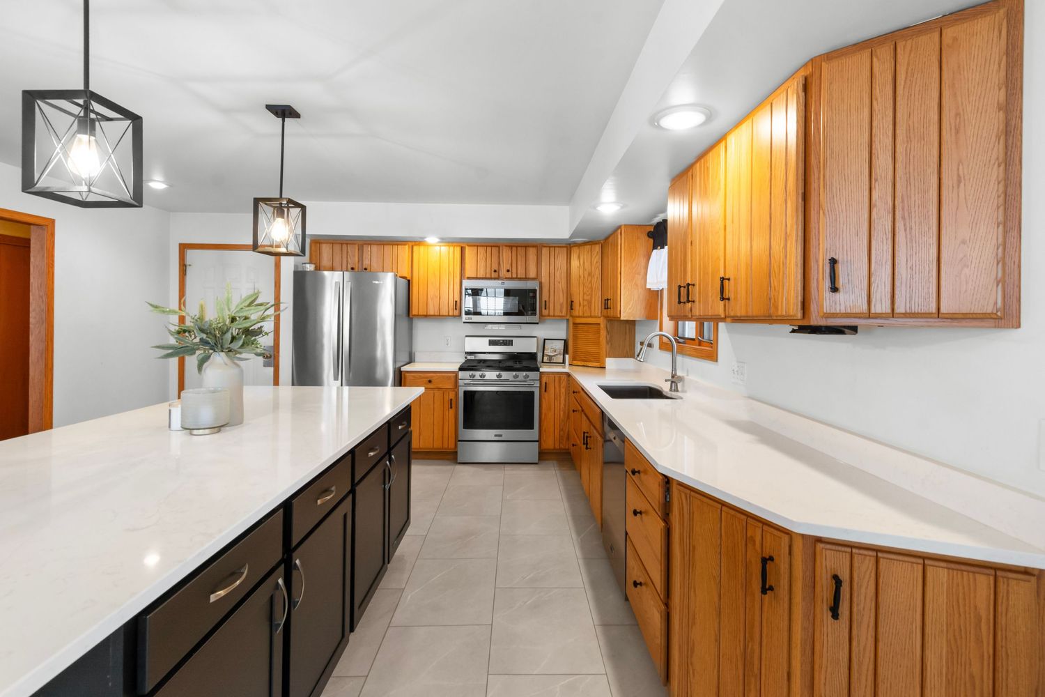 Contemporary kitchen with wood cabinets, white countertops, and pendant lighting.