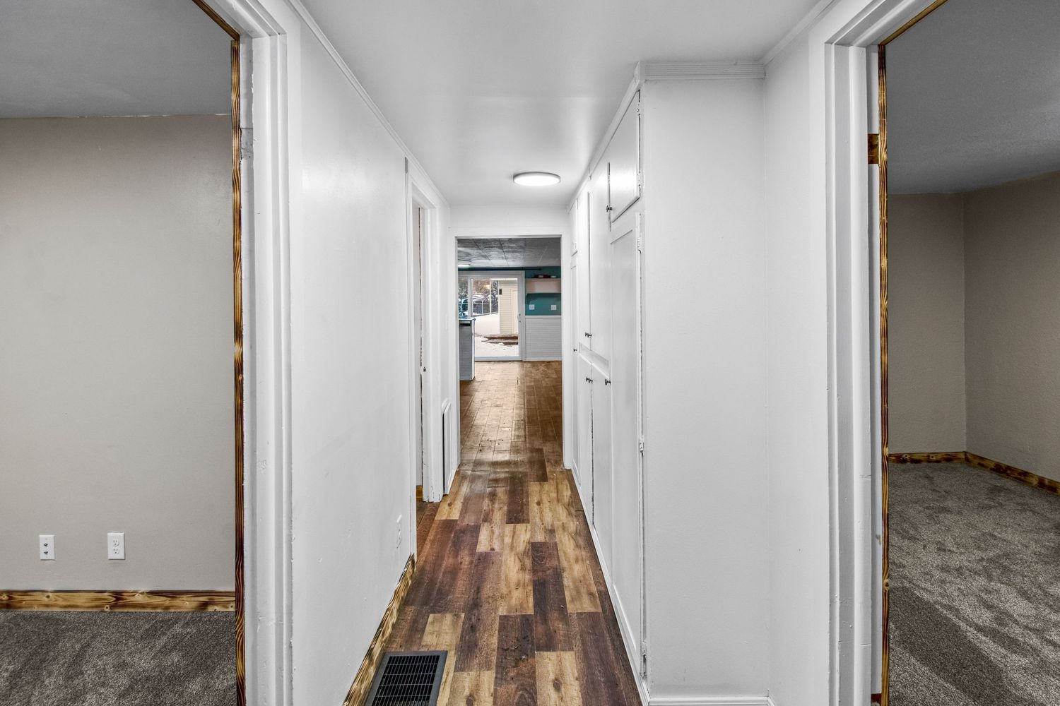 Modern hallway with white walls, dark wood flooring and multiple doorways.