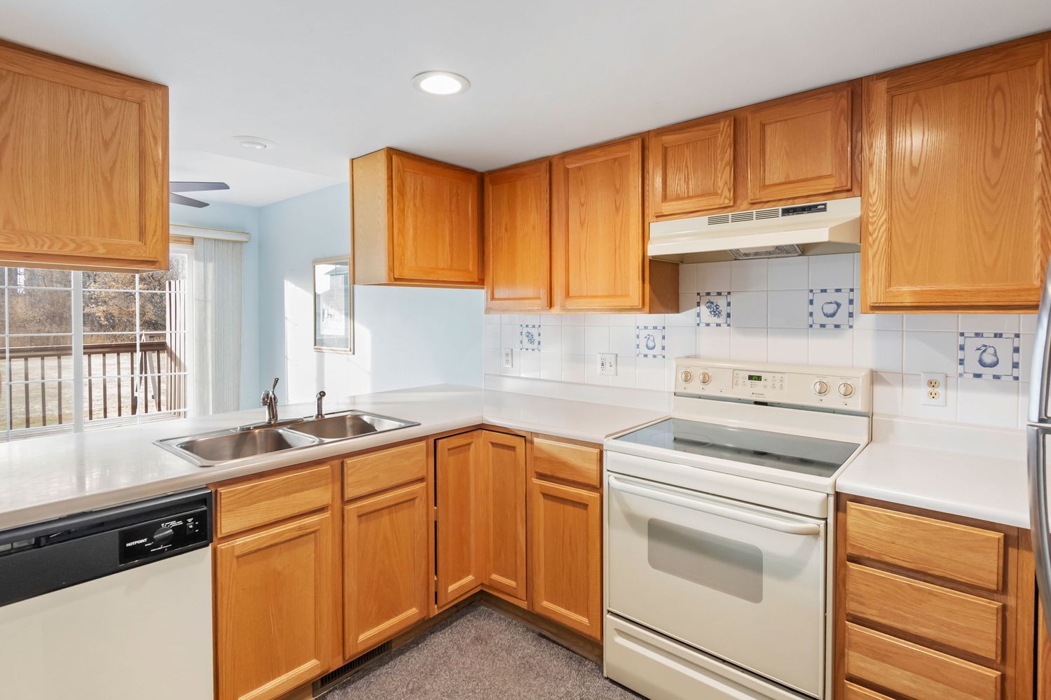 Modern kitchen with honey oak cabinets, white appliances, and laminate countertops.