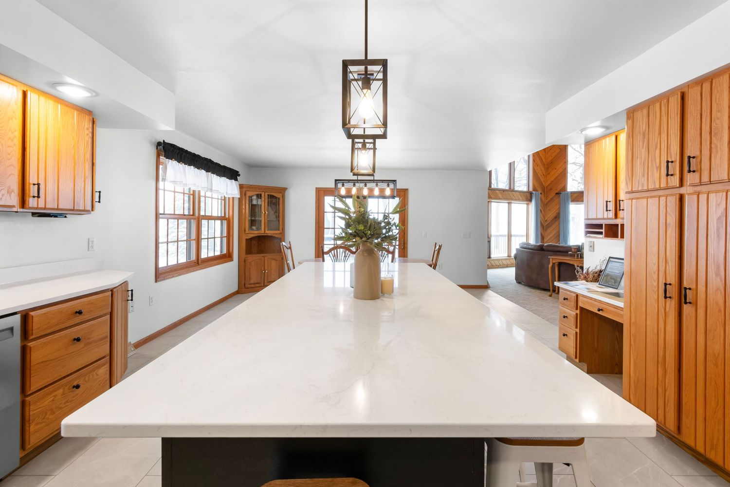Expansive kitchen with wood cabinetry, pendant lighting, and white countertops.