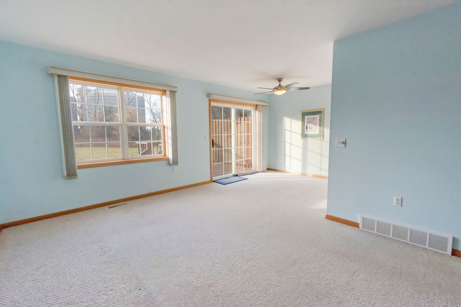 Open concept living space with blue walls, carpeting, and large windows for natural light.