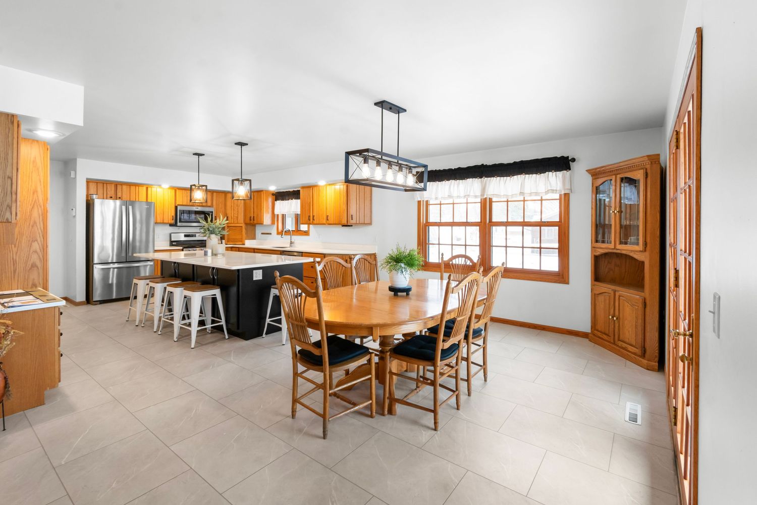 Open concept kitchen and dining area with wooden furniture and modern fixtures.