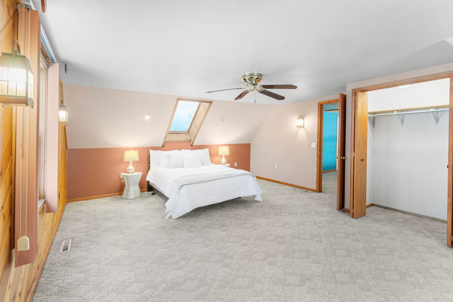 Spacious carpeted bedroom with vaulted ceilings, natural light, and wooden accents throughout.