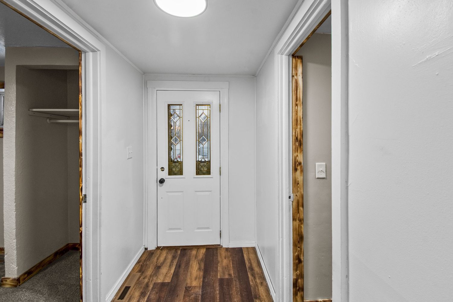 Freshly painted white hallway with natural wood trim and new flooring.