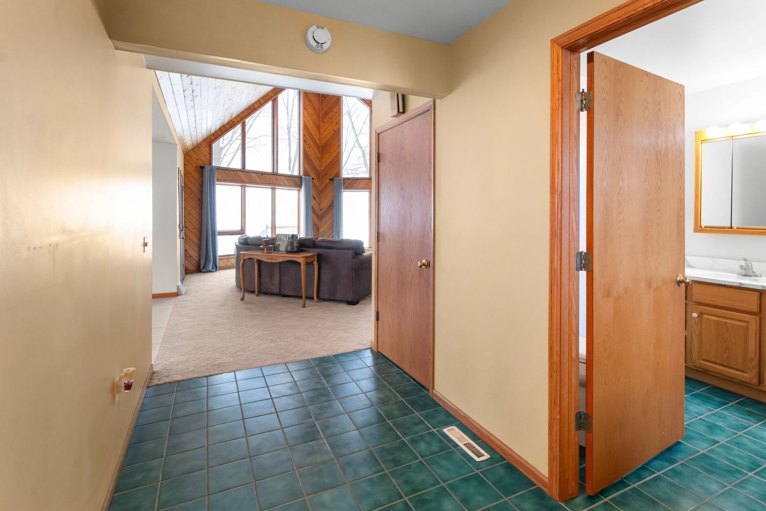 Modern hallway with beige walls and teal flooring leading to multiple doorways.
