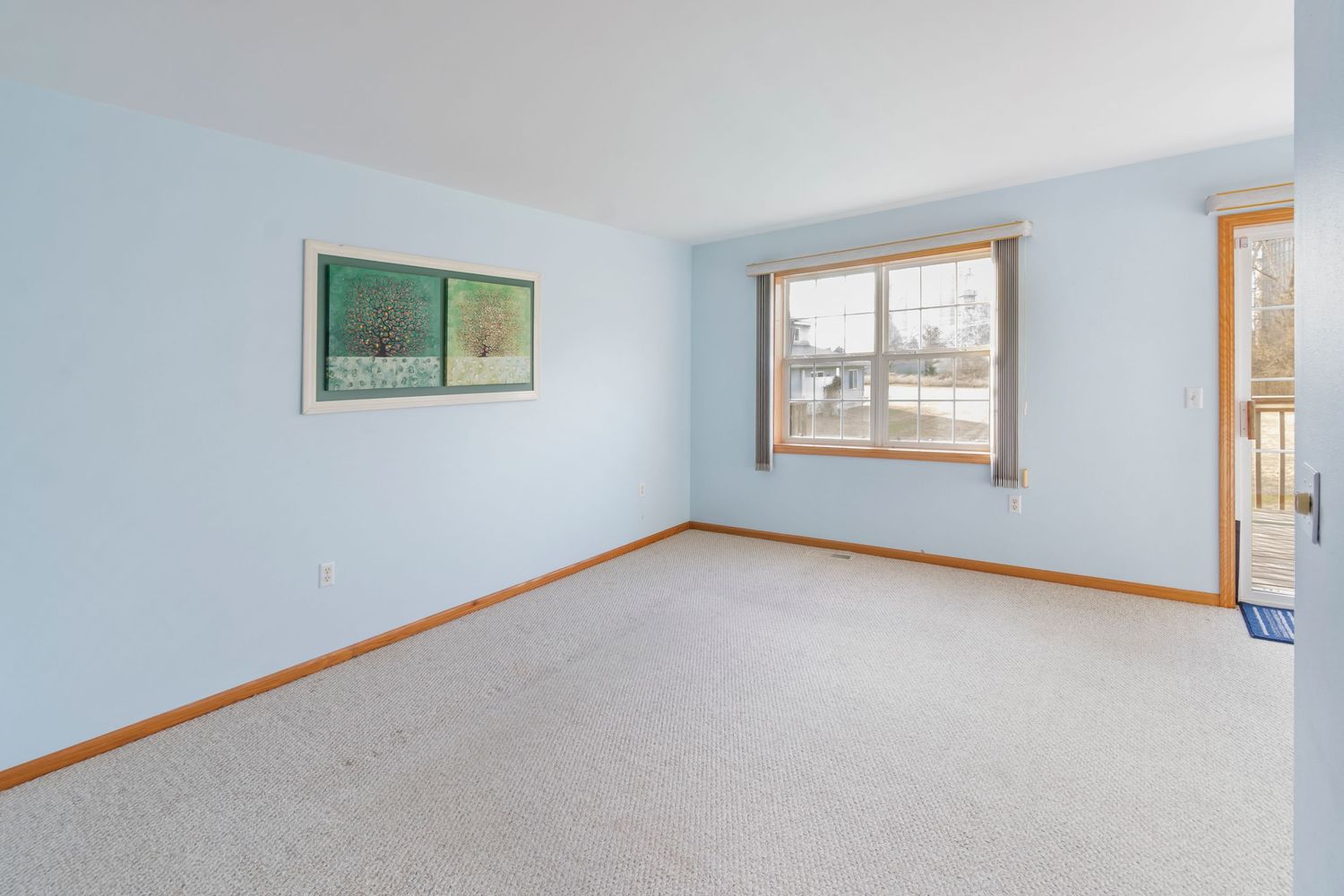 Empty interior room with white walls, wood trim, and multiple windows letting in natural light.