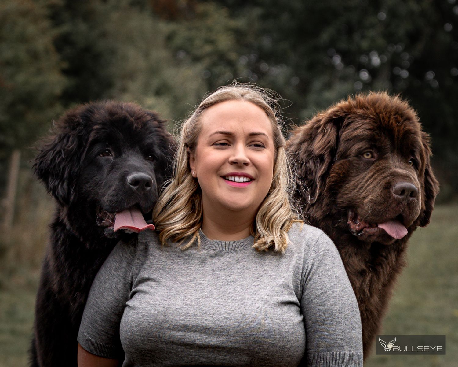 Two large fluffy dogs posing outdoors with their companion between them.