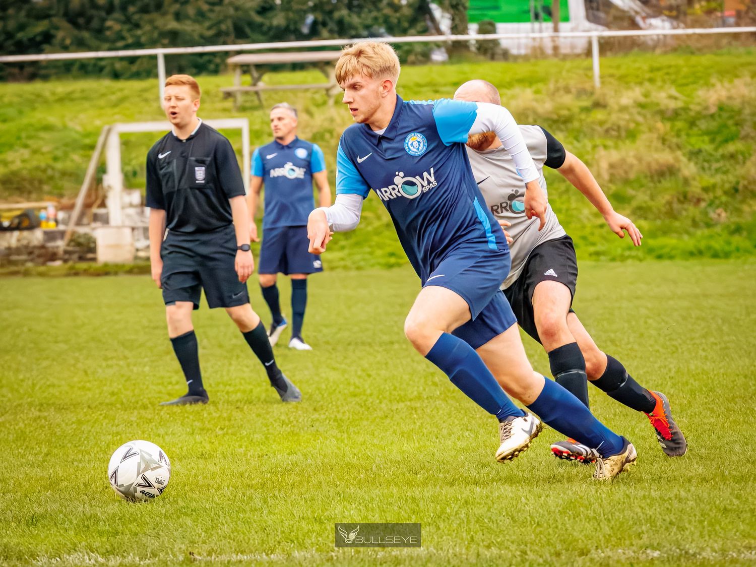 Soccer players compete for possession of the ball during an intense match on a grassy field.