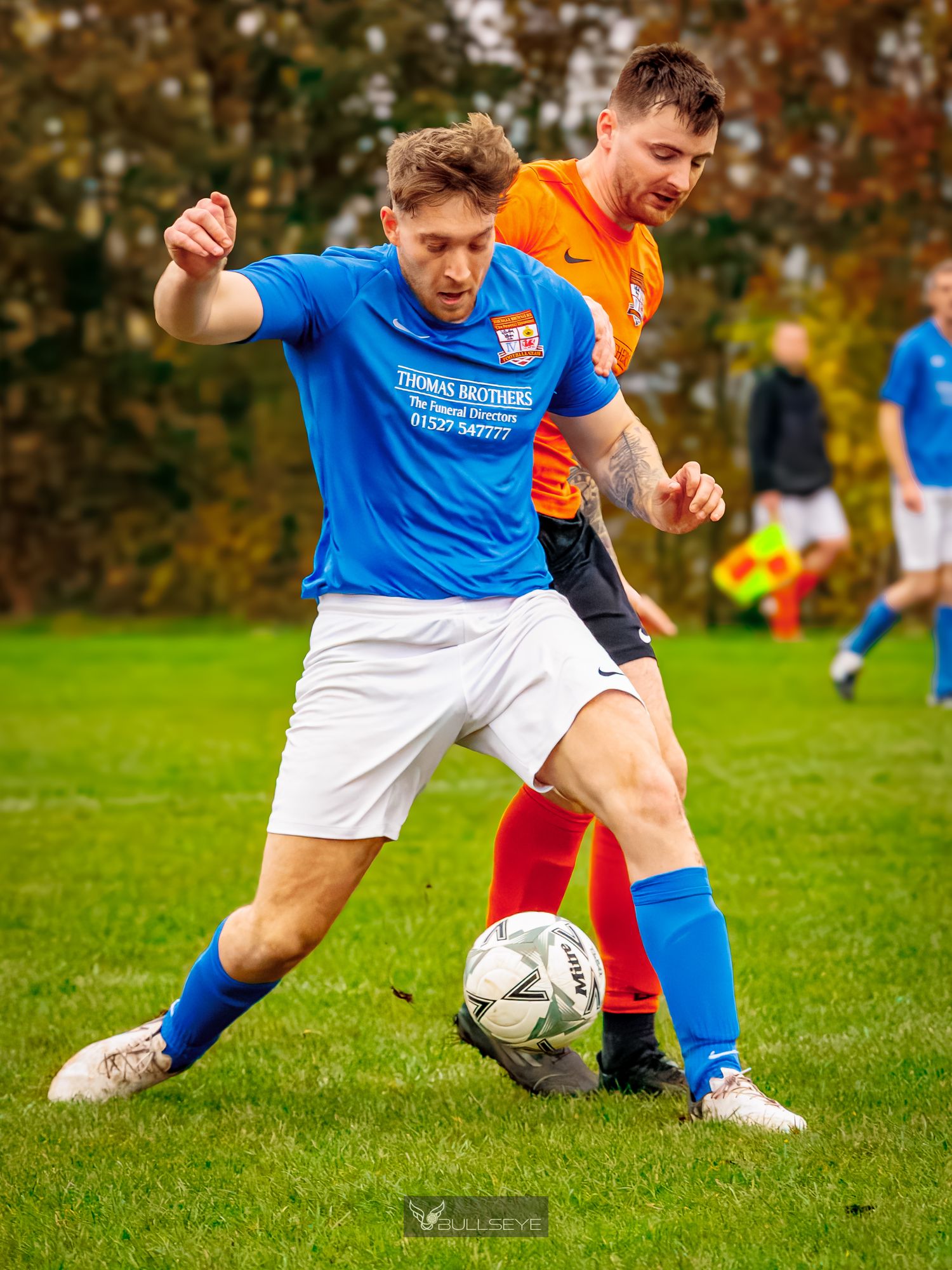 Soccer players compete for possession of the ball during an intense match on a grass field.
