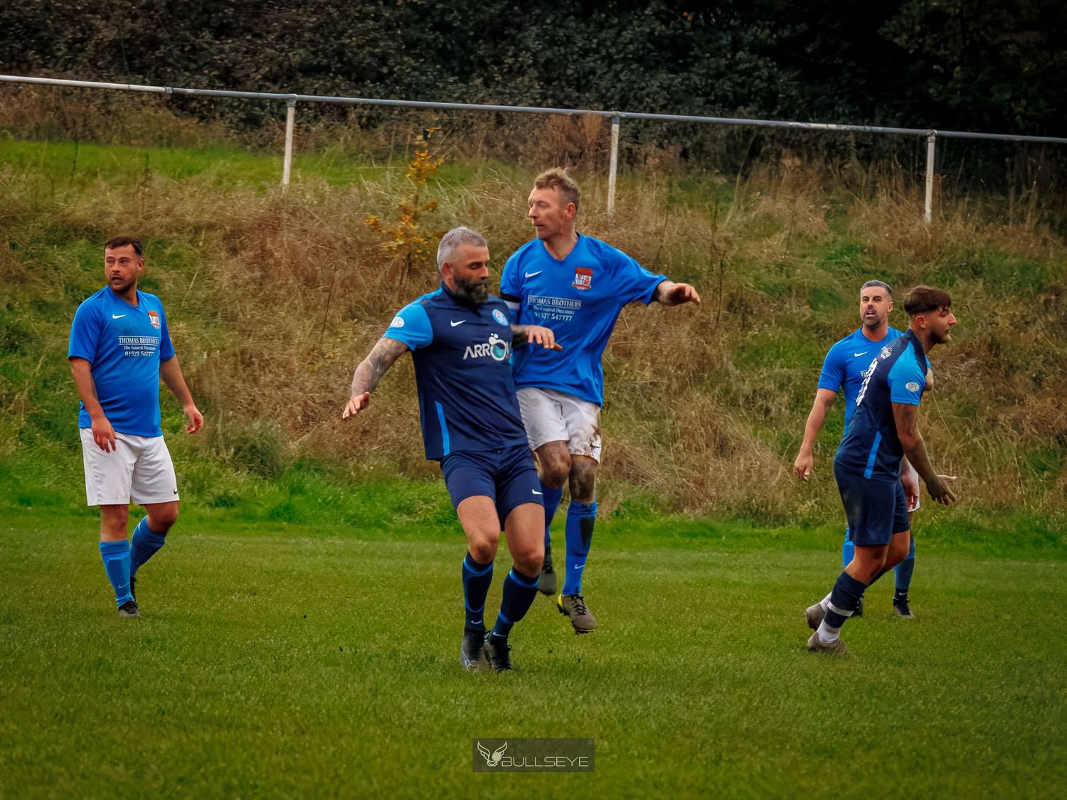 Soccer players chase after the ball during an intense match on a grassy field.