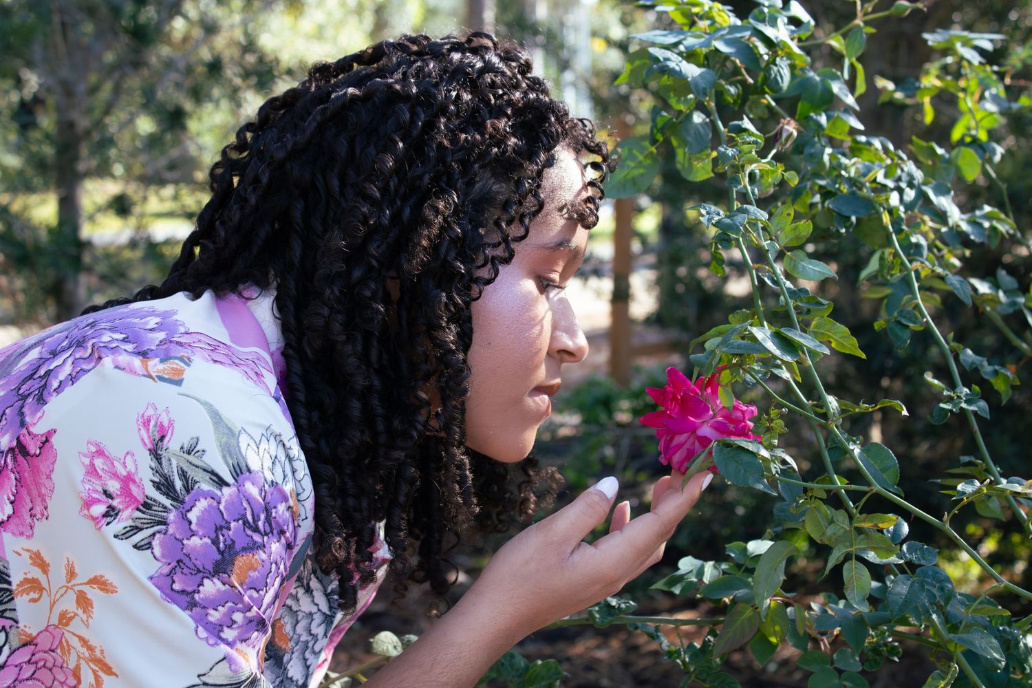 A floral photoshoot in a garden setting with white roses and a pink floral dress.