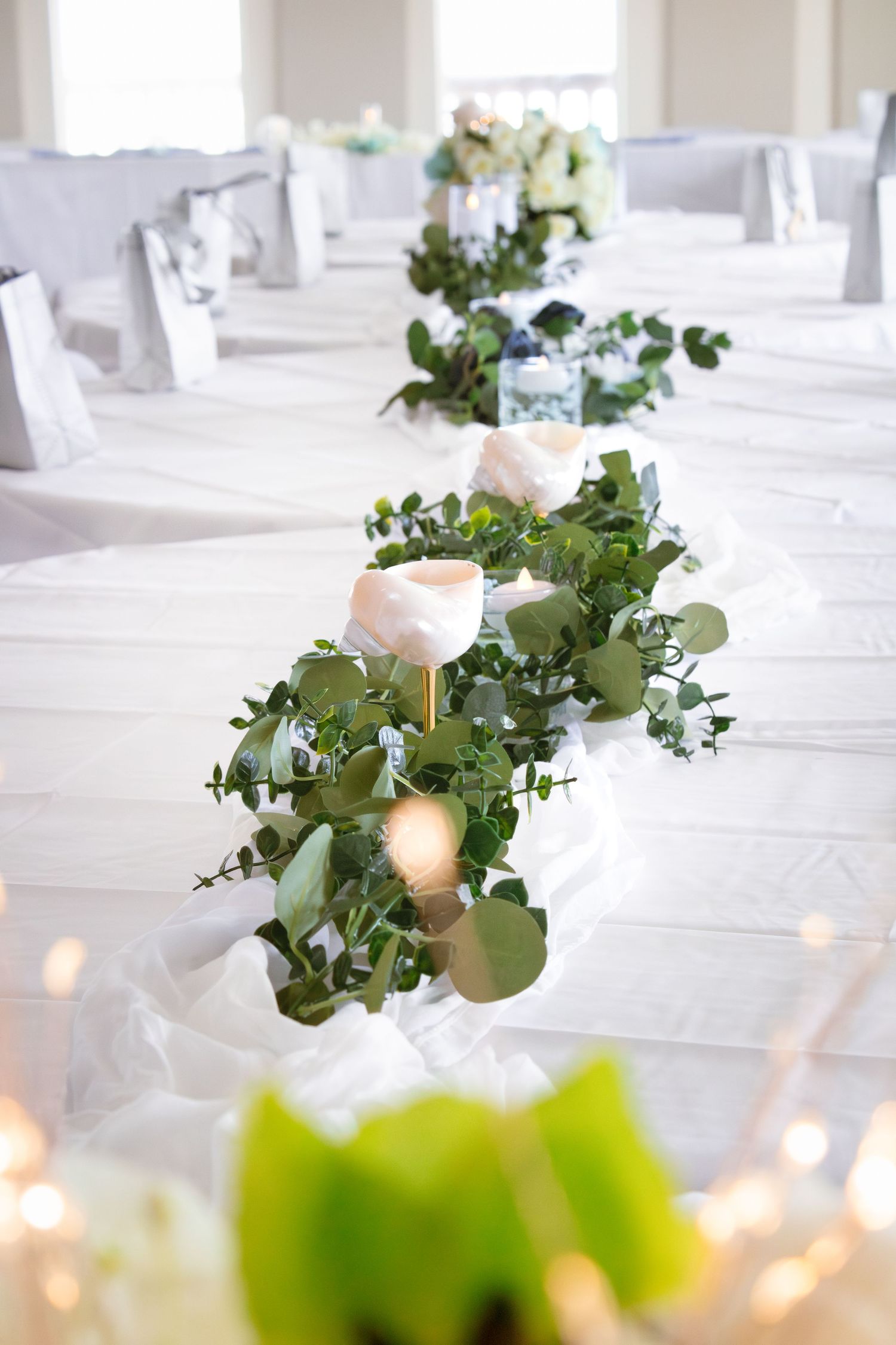 Elegant wedding table settings with eucalyptus centerpieces and white linens.