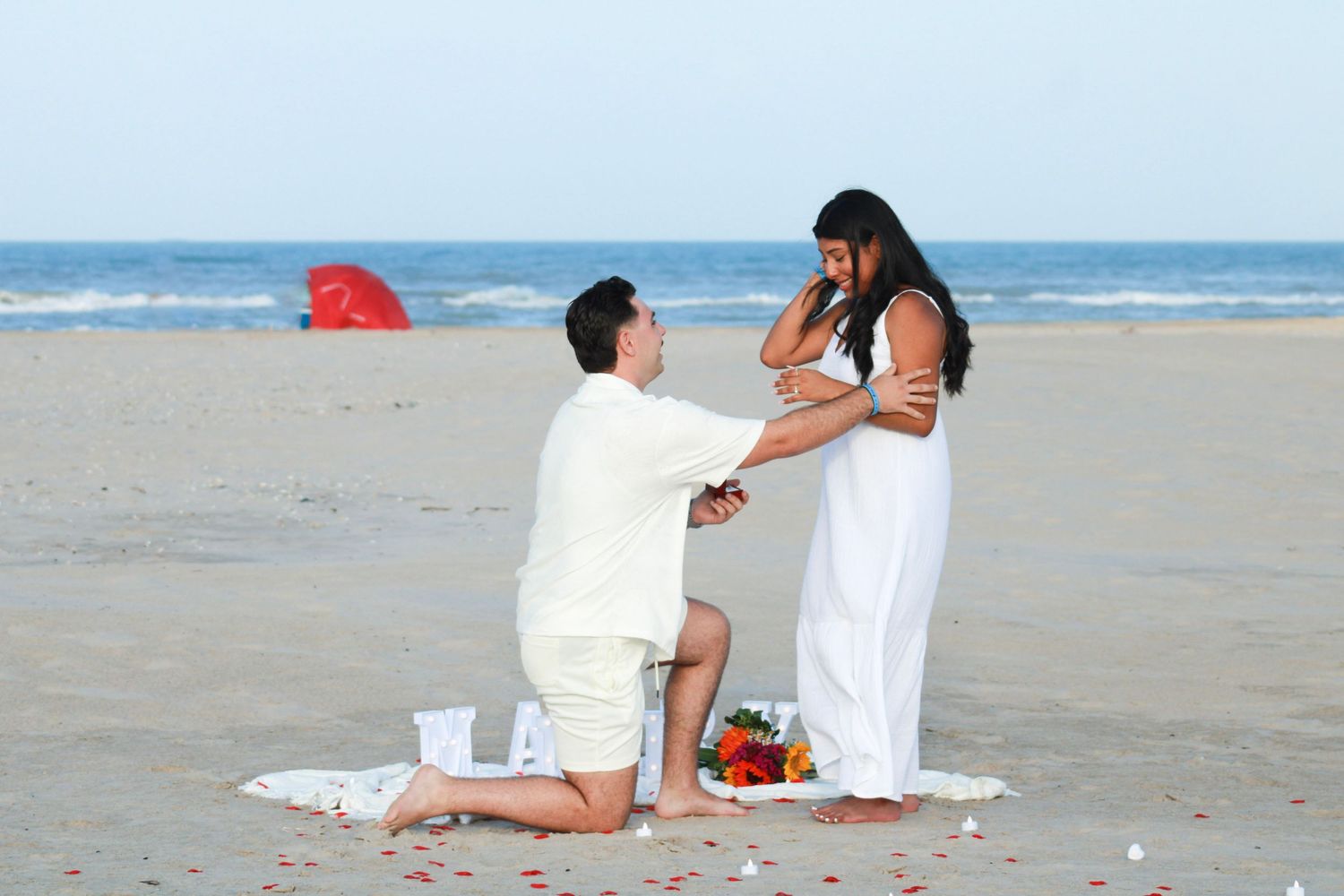 Couple sharing an intimate moment on beach blanket with ocean view.