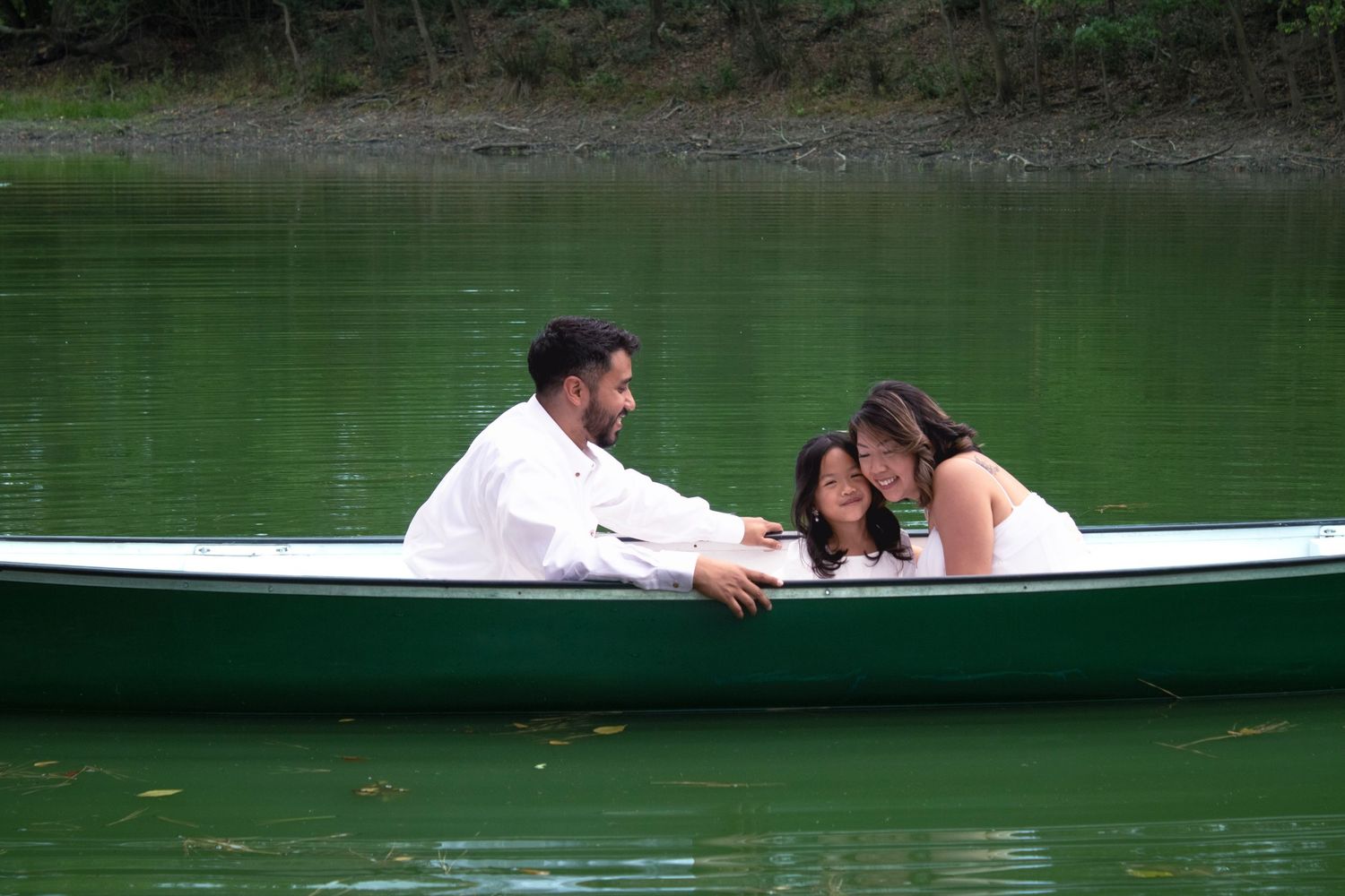 Couple enjoys a peaceful moment together in a white rowboat on a green lake.