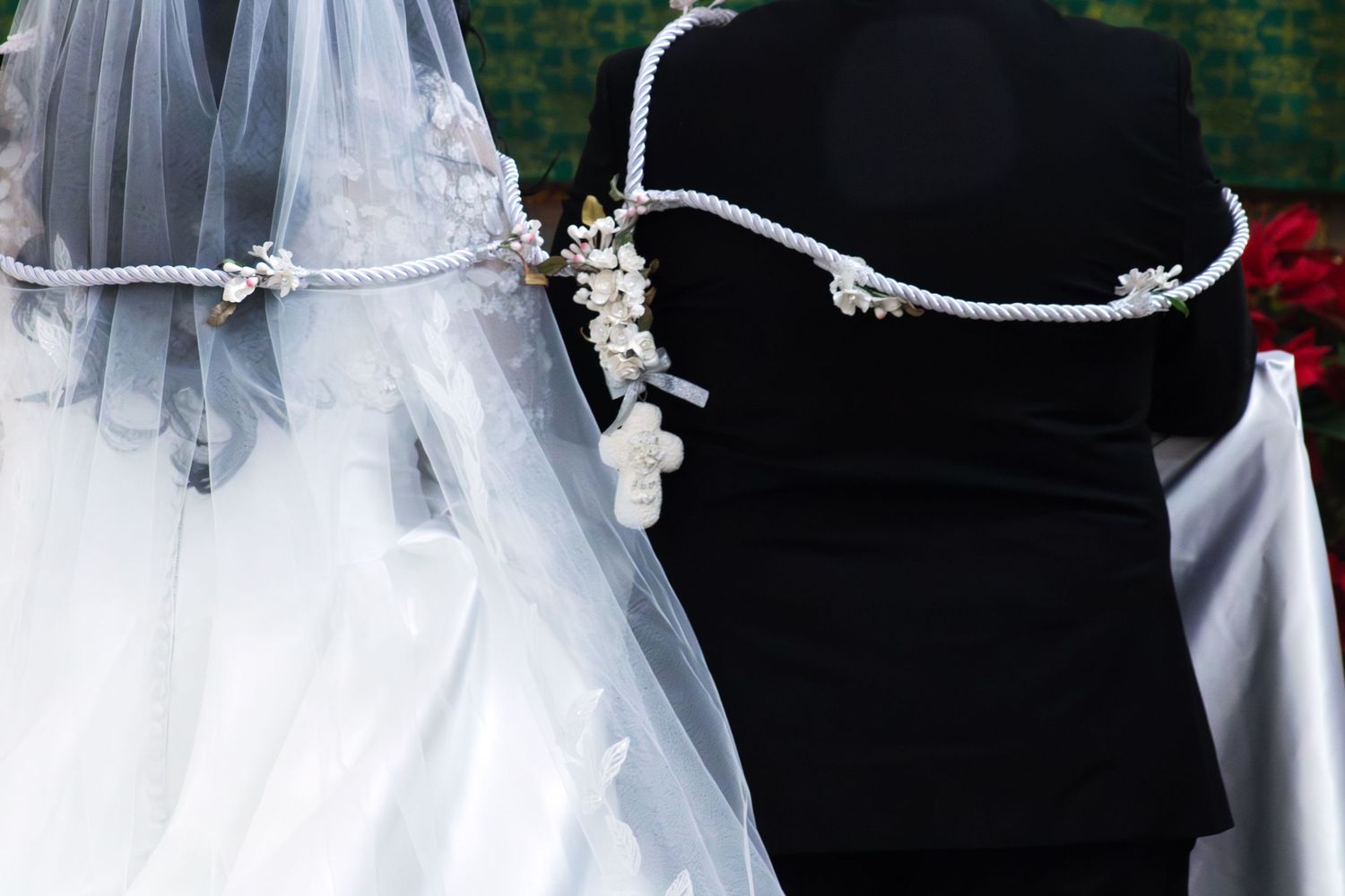 Close-up details of a bride's veil and wedding dress during a church ceremony.