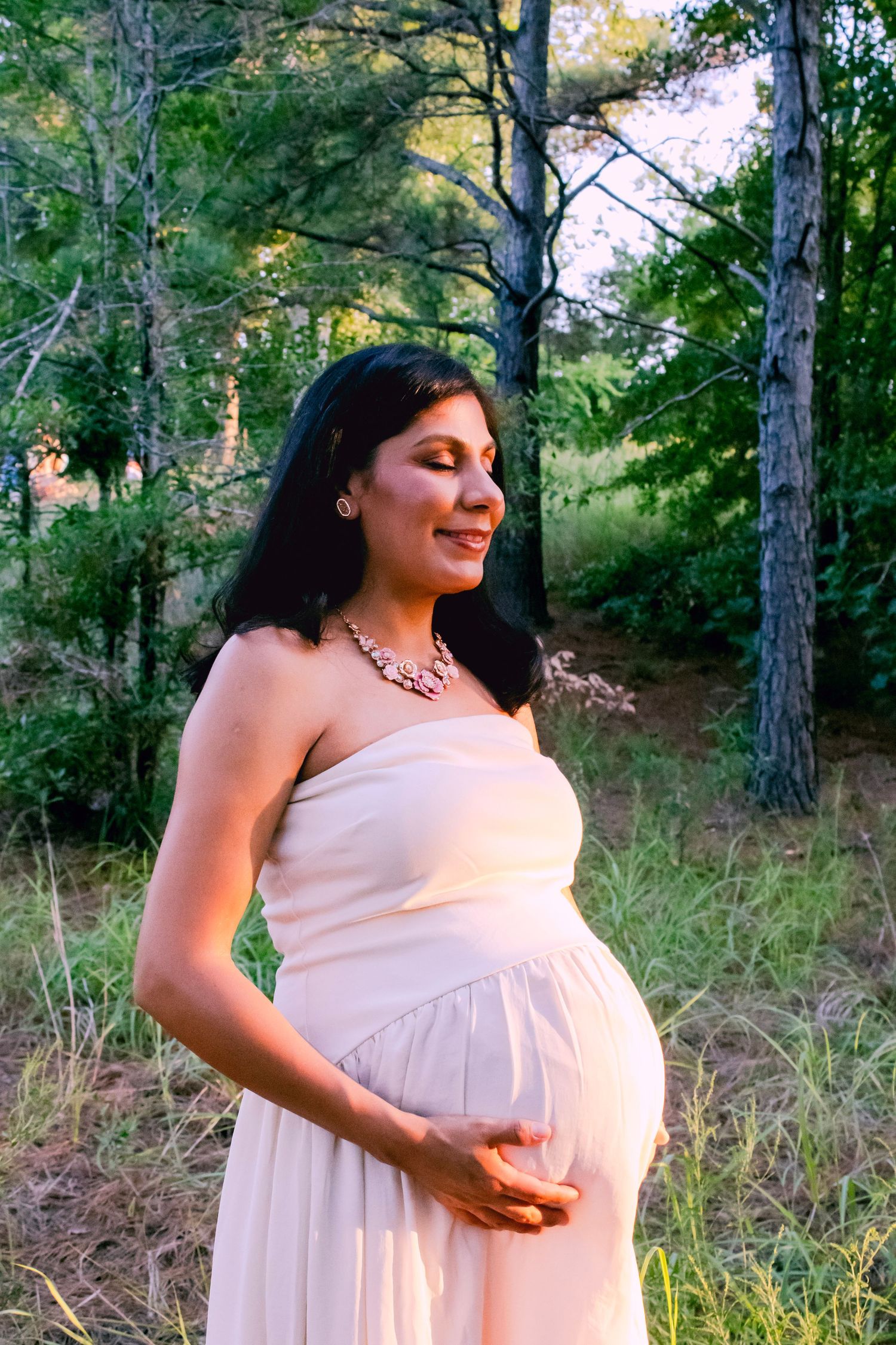 A joyful maternity photo session captured in a serene wooded setting during golden hour.