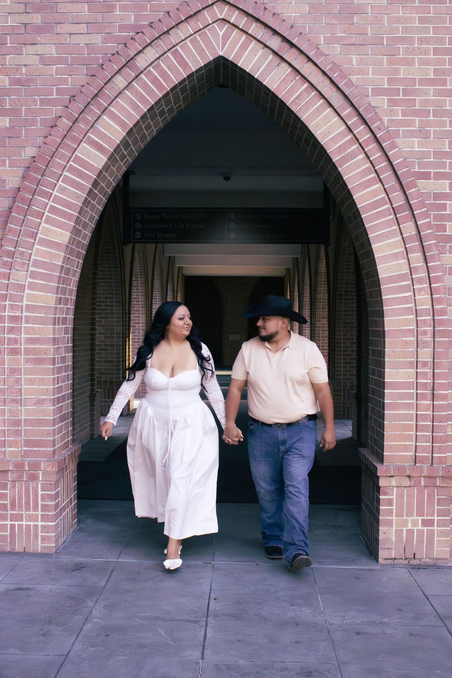 A couple walking through brick archways in a romantic photo sequence.