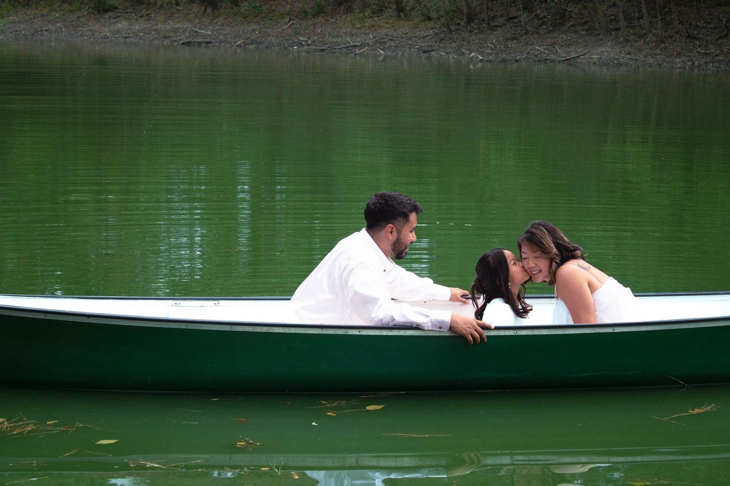 Couple in white clothing relaxes together in rowboat surrounded by calm green waters.