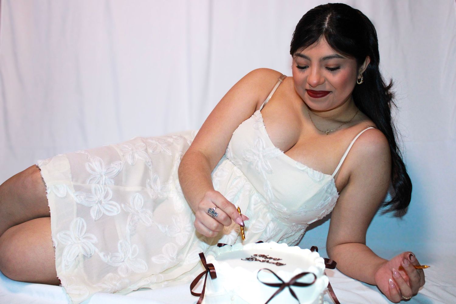 A person in white enjoys cake during a photo session with decorative elements.
