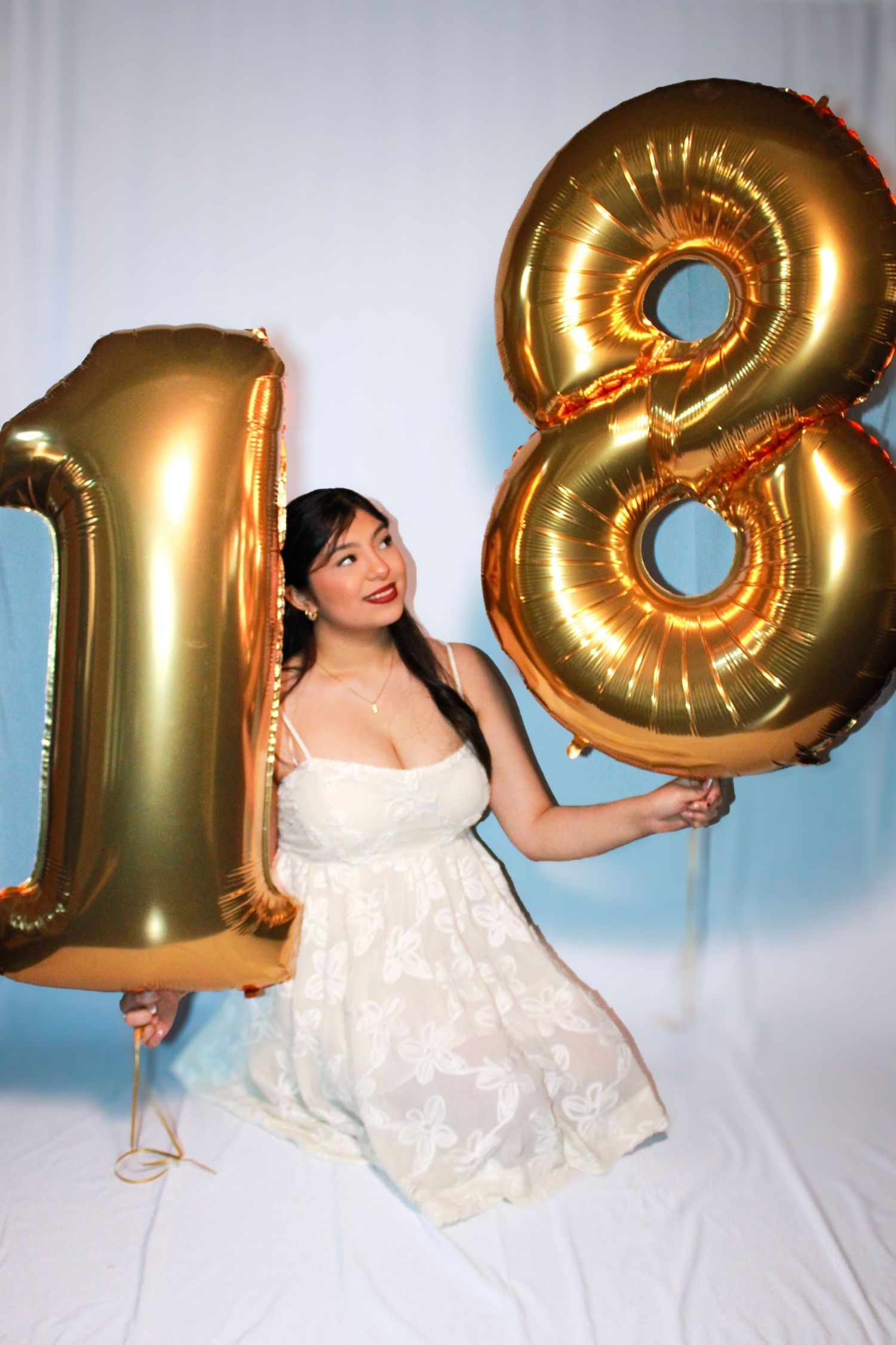 Celebratory photos with gold balloon numbers and white dress against studio backdrop.