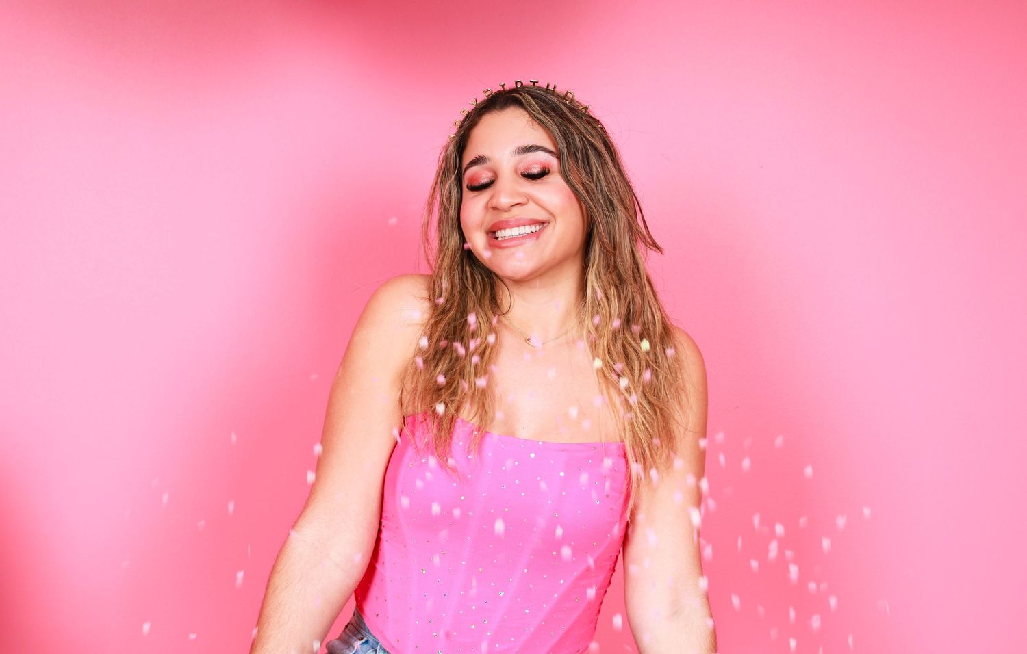 Celebratory poses with confetti against pink background in photo series.