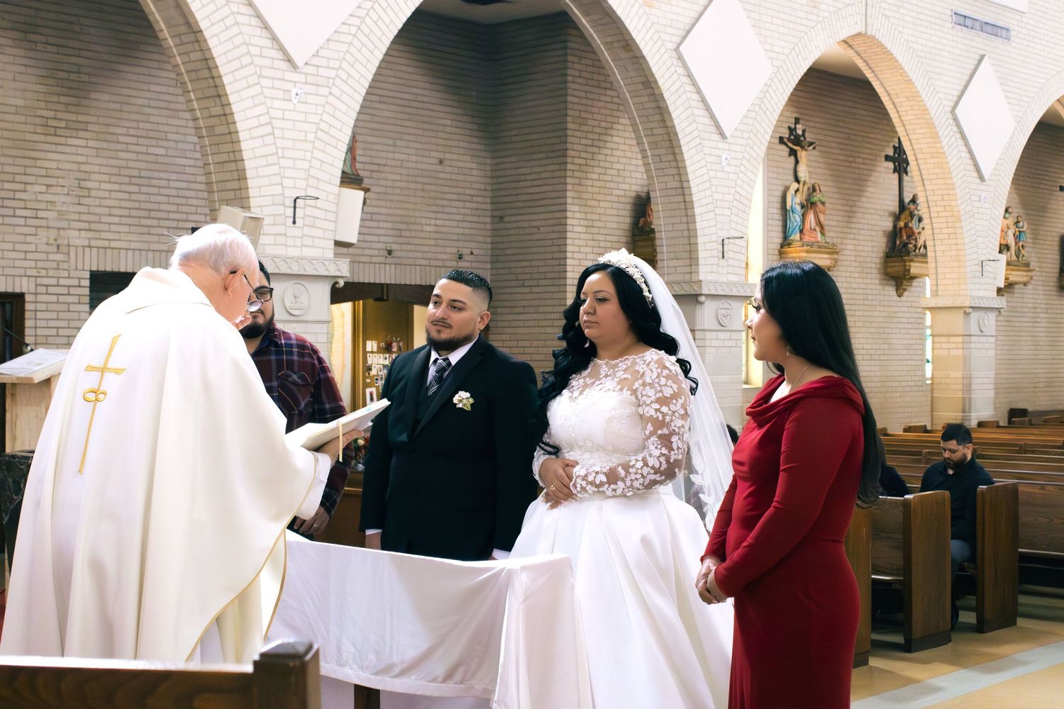 Religious ceremony participants stand beneath stone arches in a traditional church setting.