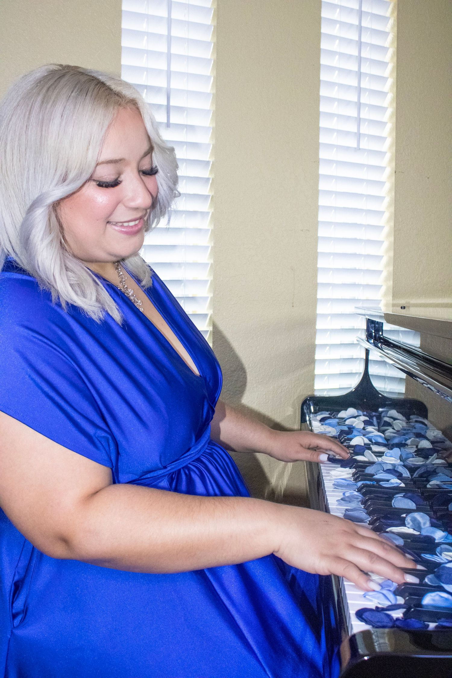 Someone in a bright blue top sorting through photographs at a desk.