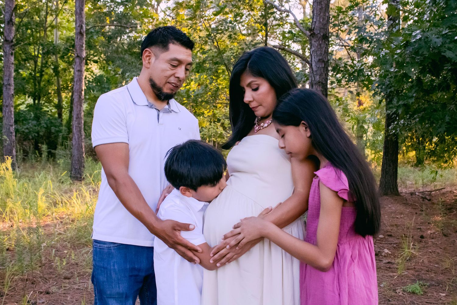 Family members embracing in a natural outdoor setting with trees in background.