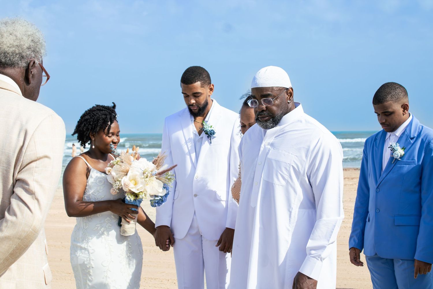 Wedding party members in white and blue attire standing together outdoors.