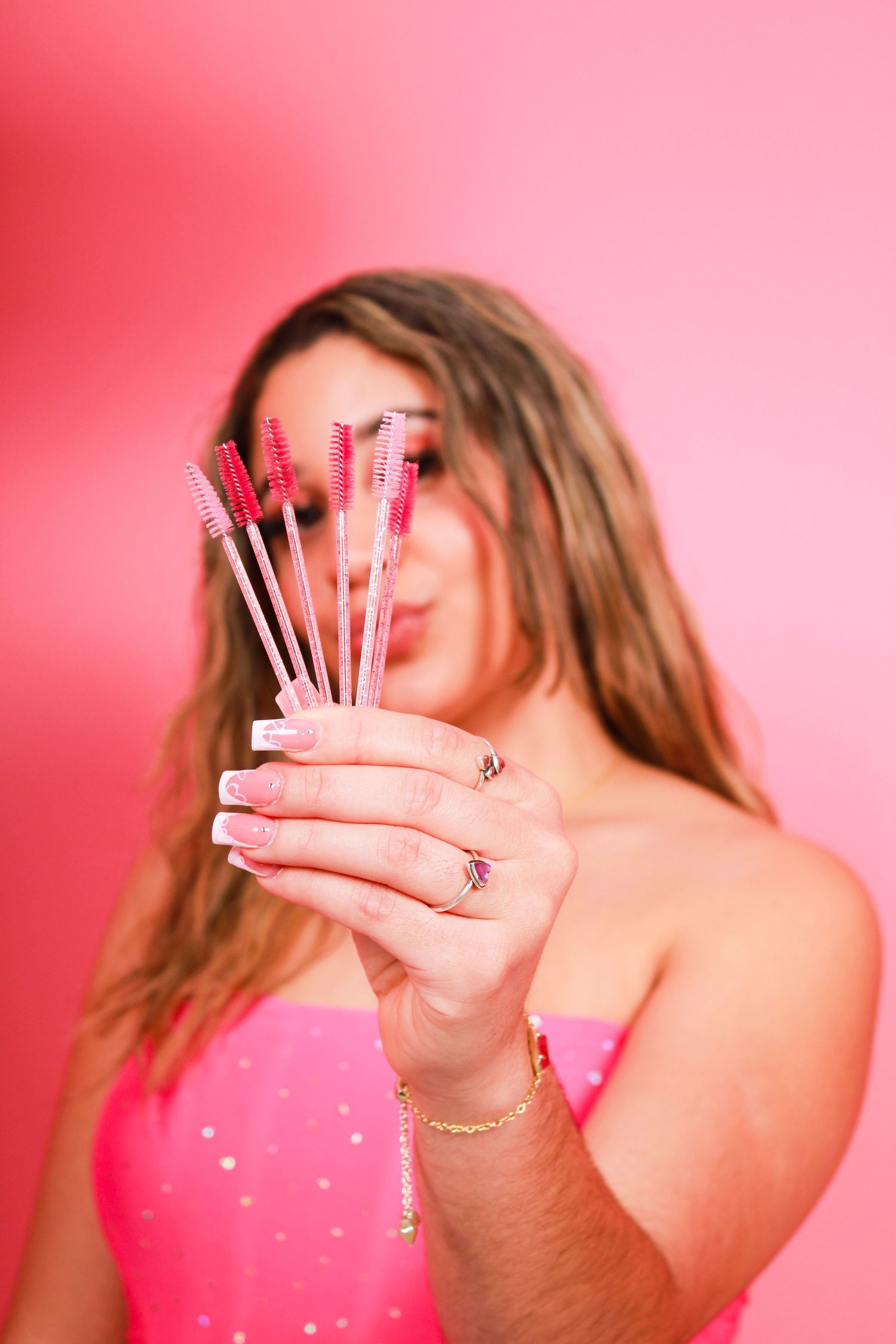 Hands holding sparklers in sequence against pink background.