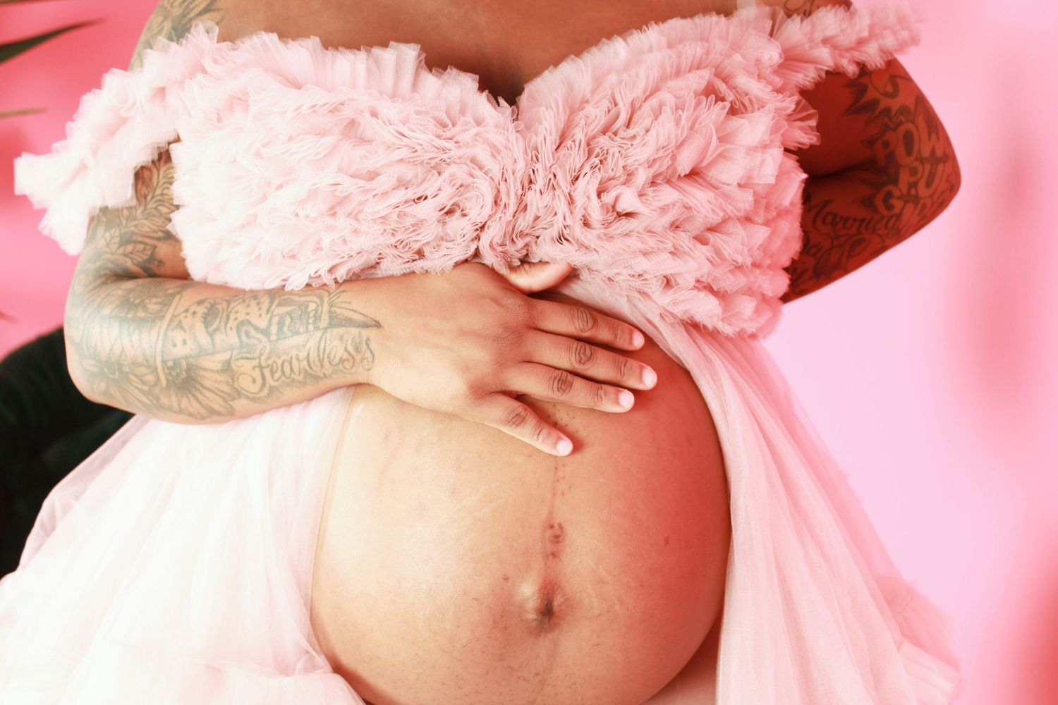 Close-up maternity photo with soft pink tulle fabric and natural lighting.