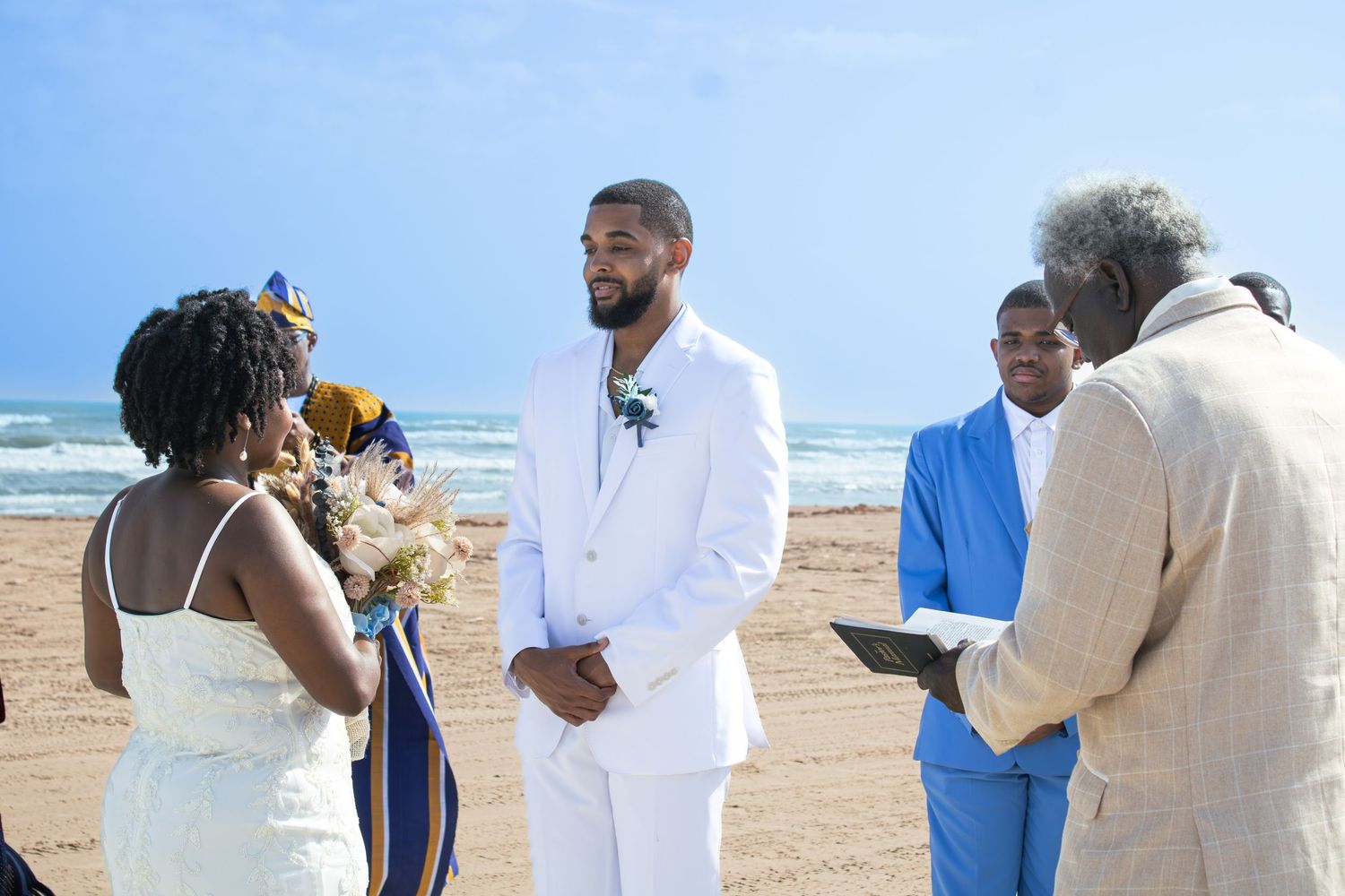 A beach wedding ceremony with the ocean and blue sky in the background.